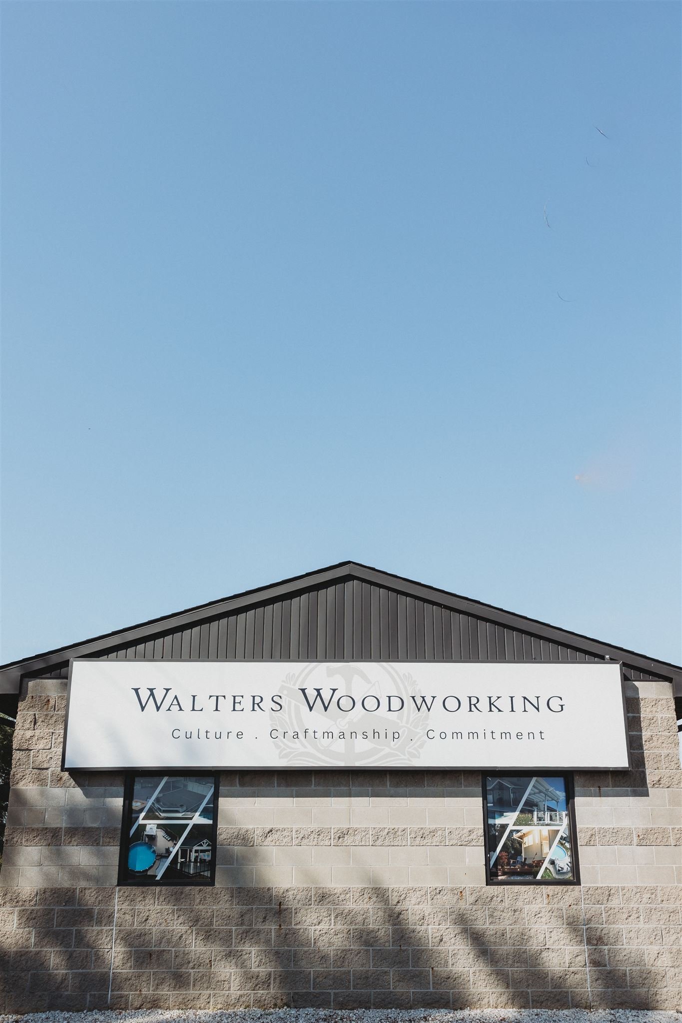 Exterior storefront of Walters Woodworking, a custom woodworking and craftsmanship business, featuring a bold branded sign with their tagline "Culture. Craftmanship. Commitment" on a stone building facade.