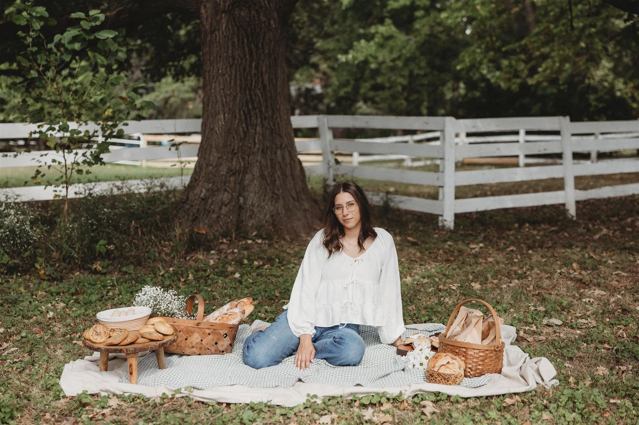 Wild Flour Sourdough Bakehouse owner seated on a picnic blanket surrounded by sourdough bread and wicker baskets outdoors — brand photography, Central Illinois