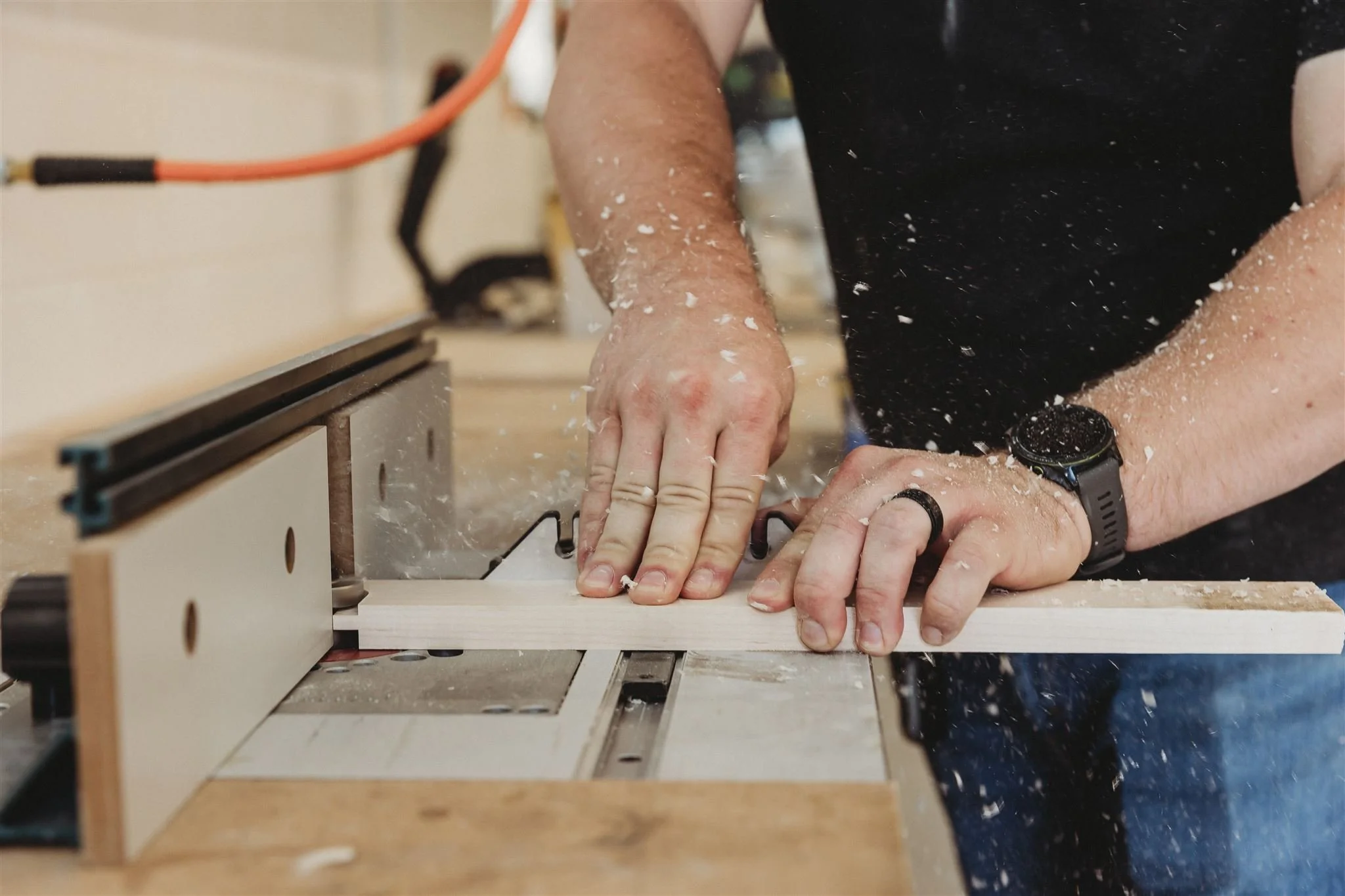 A Walters Woodworking craftsman precision-cutting wood on a table saw with sawdust flying, demonstrating the skilled hands-on craftsmanship behind their custom cabinetry and millwork production.