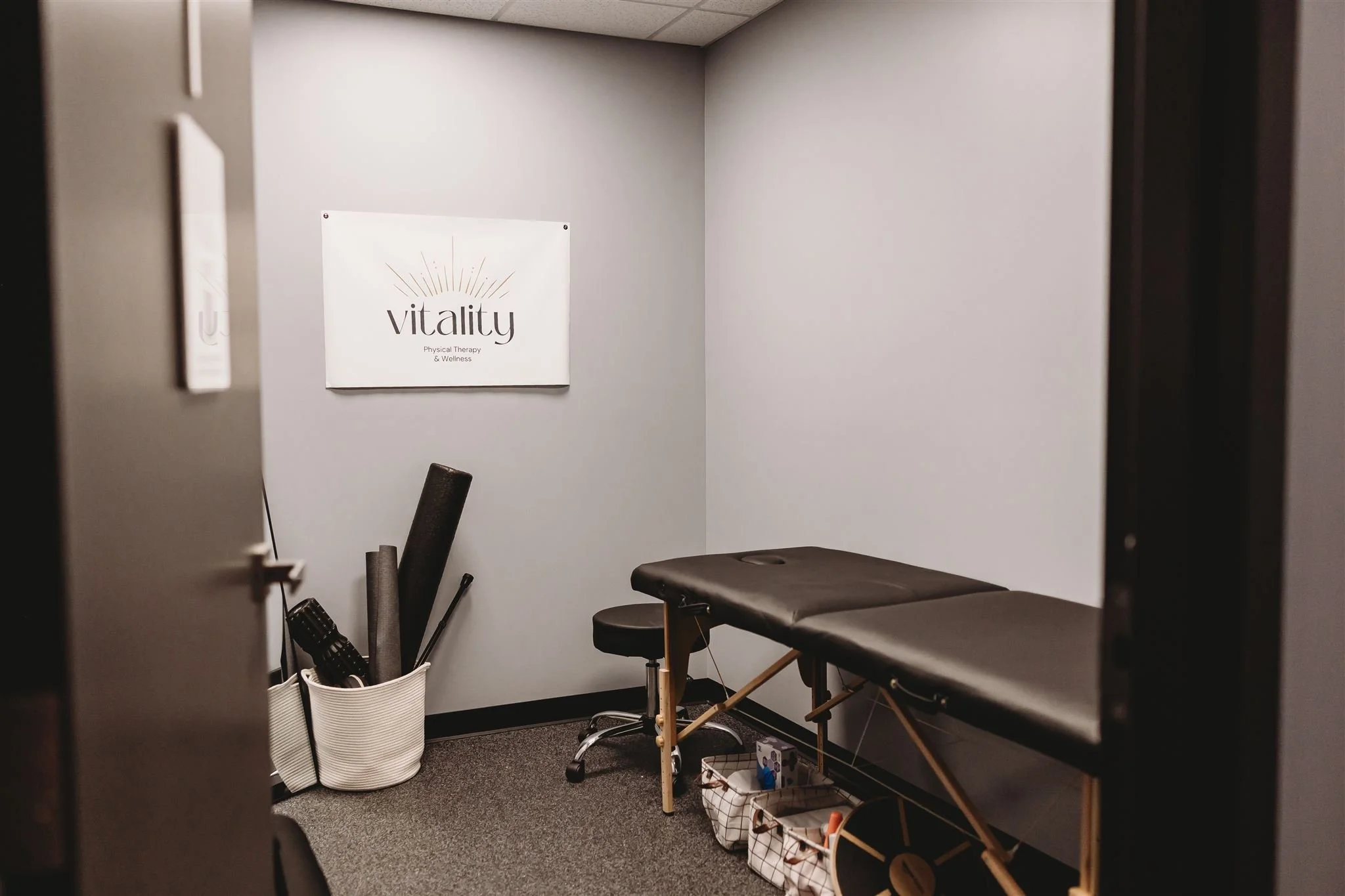 A private Vitality Physical Therapy and Wellness treatment room featuring a physiotherapy table, foam rollers, and therapy tools