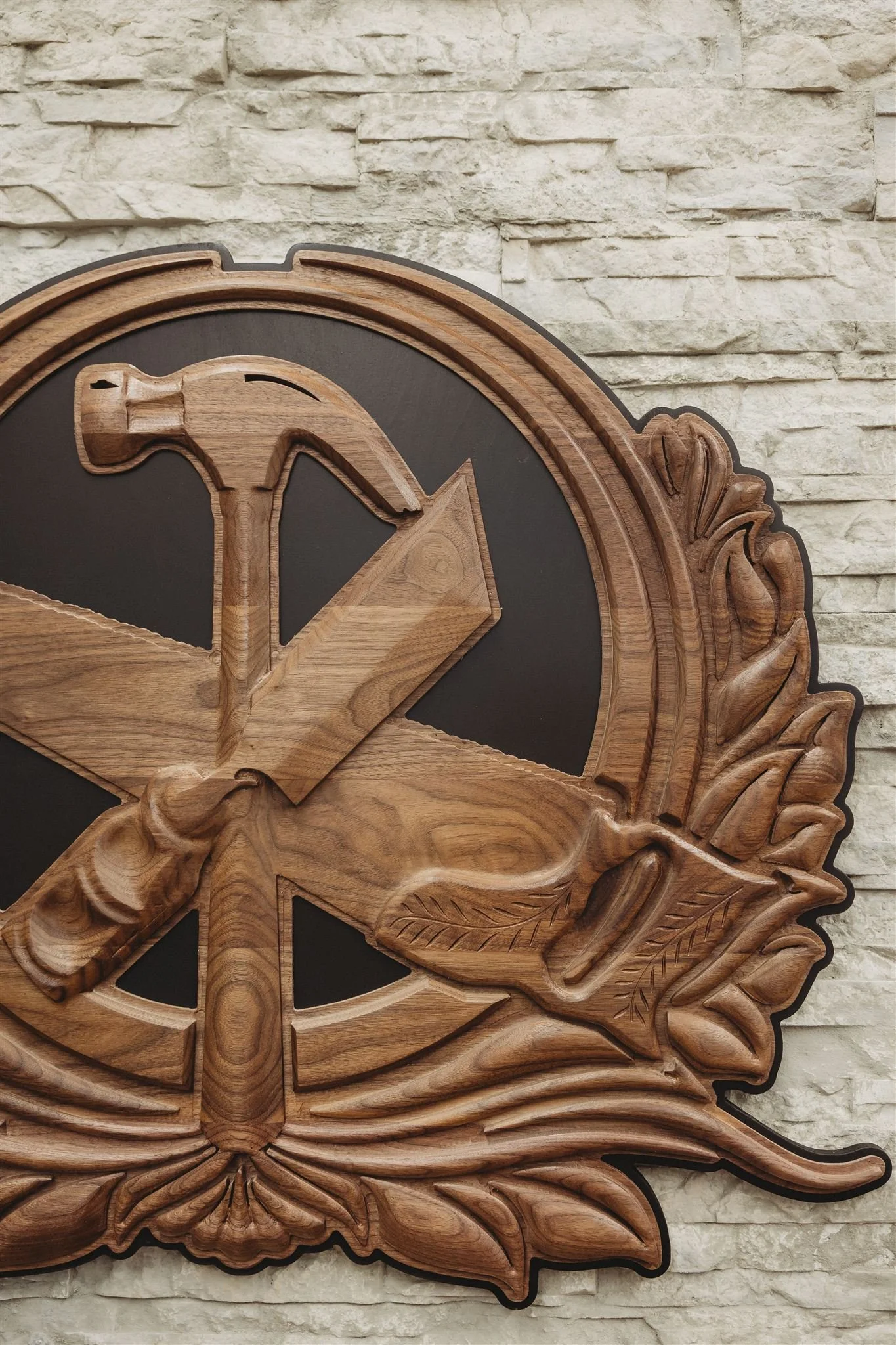 Wooden wall clock with a hammer and saw design, hanging on a textured wall.