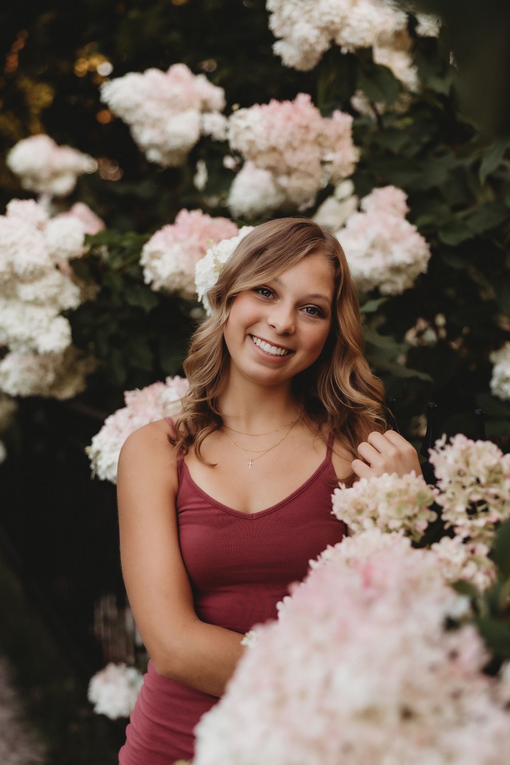  during senior portraits addie smiles standing in the middle of a hydrangea bush  