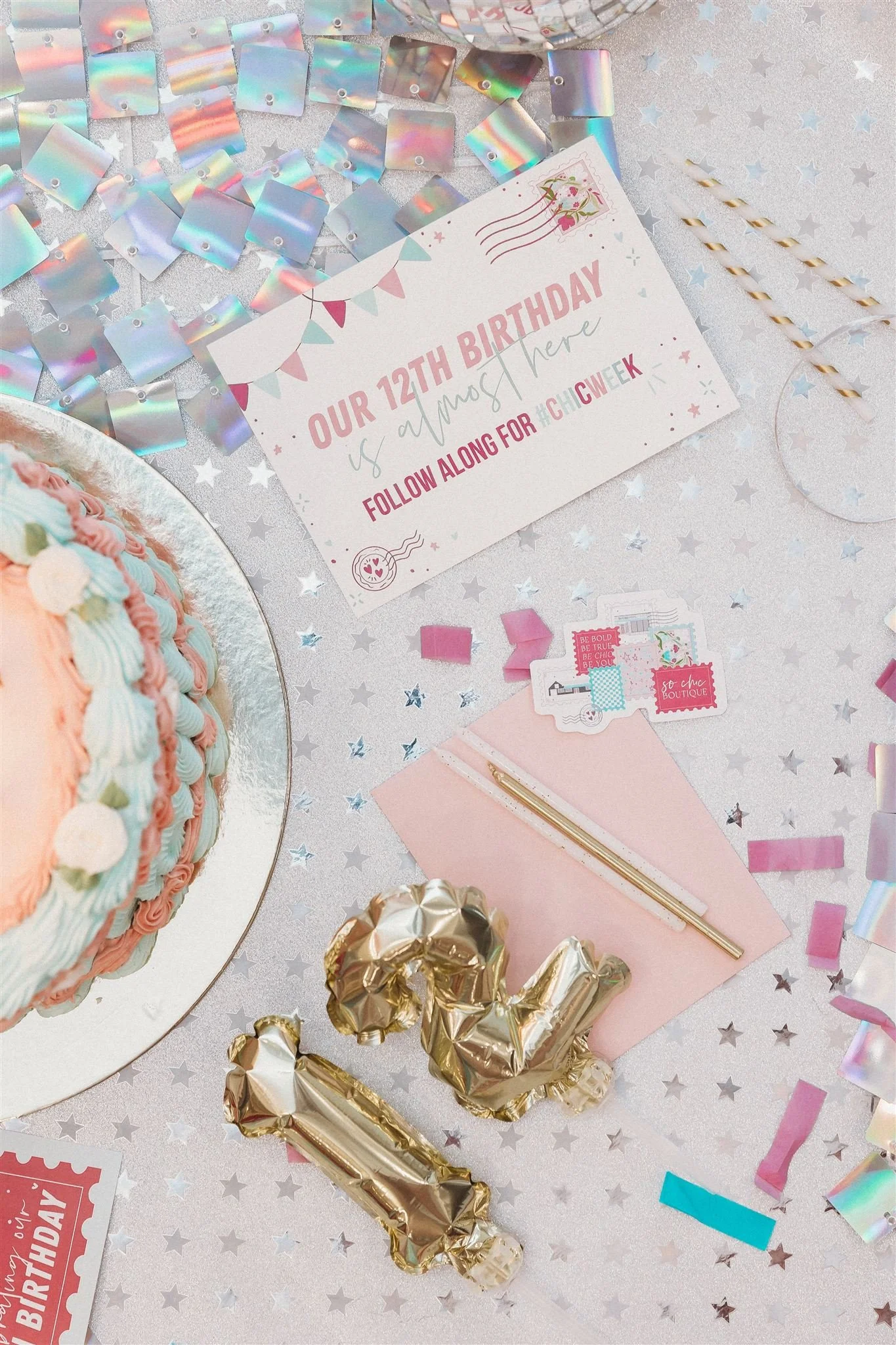 Decorative table with a pastel birthday cake, a sign that reads 'Our 12th Birthday is almost here,' gold foil balloons spelling '12,' and party decorations including confetti, ribbons, and stickers.
