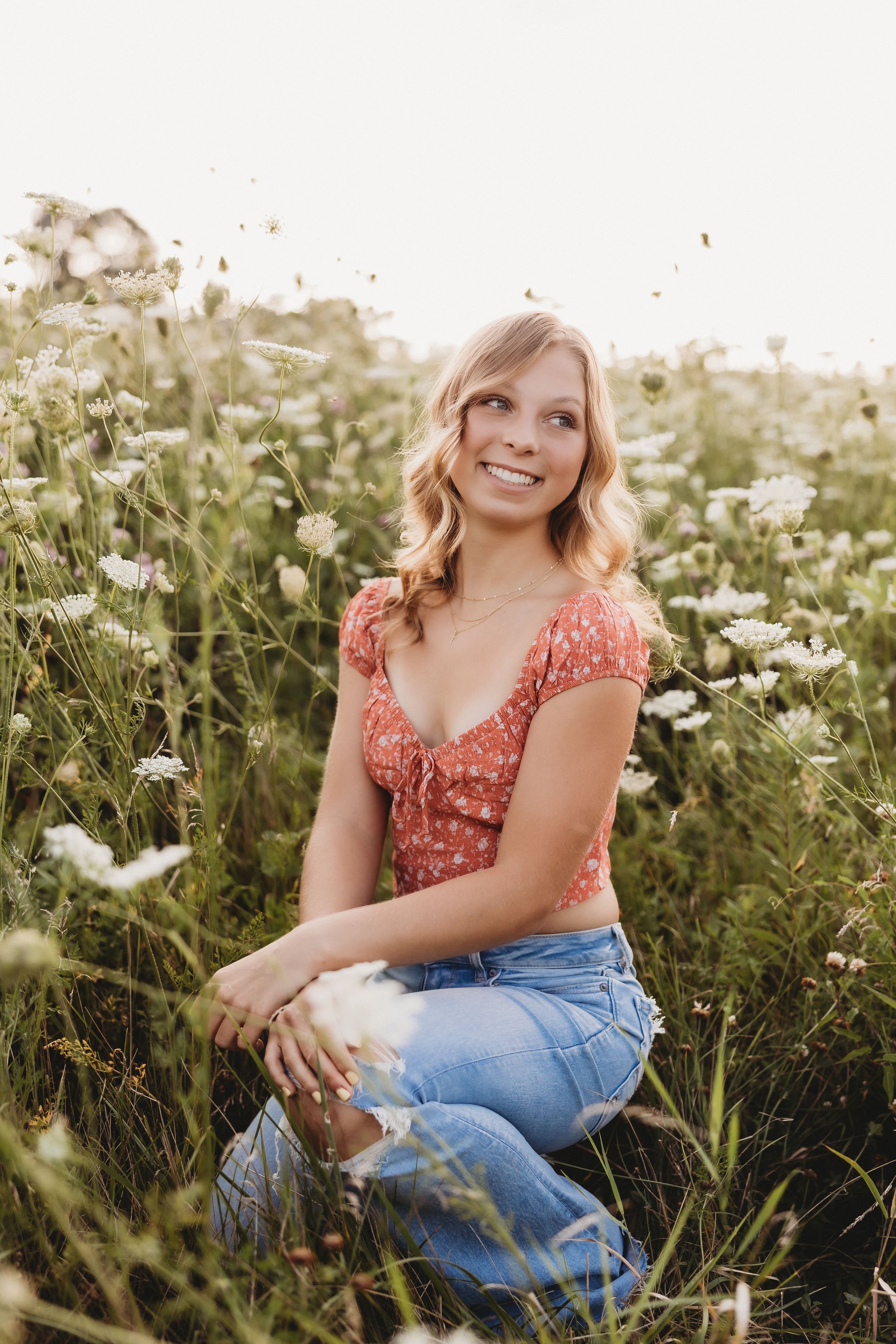  addie’s senior photographer near me captured her smiling and looking to the side in a field of wildflowers 