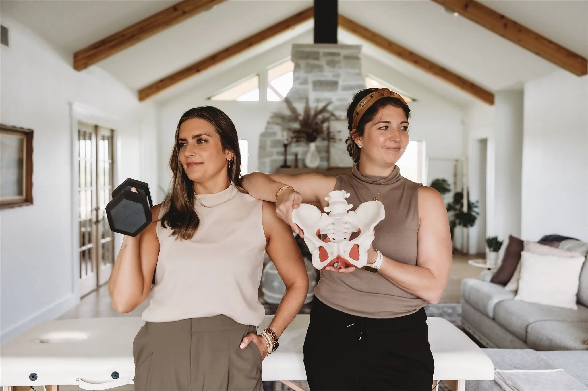 Two Vitality Physical Therapy and Wellness physiotherapists confidently posing with a dumbbell and a pelvic floor anatomical model