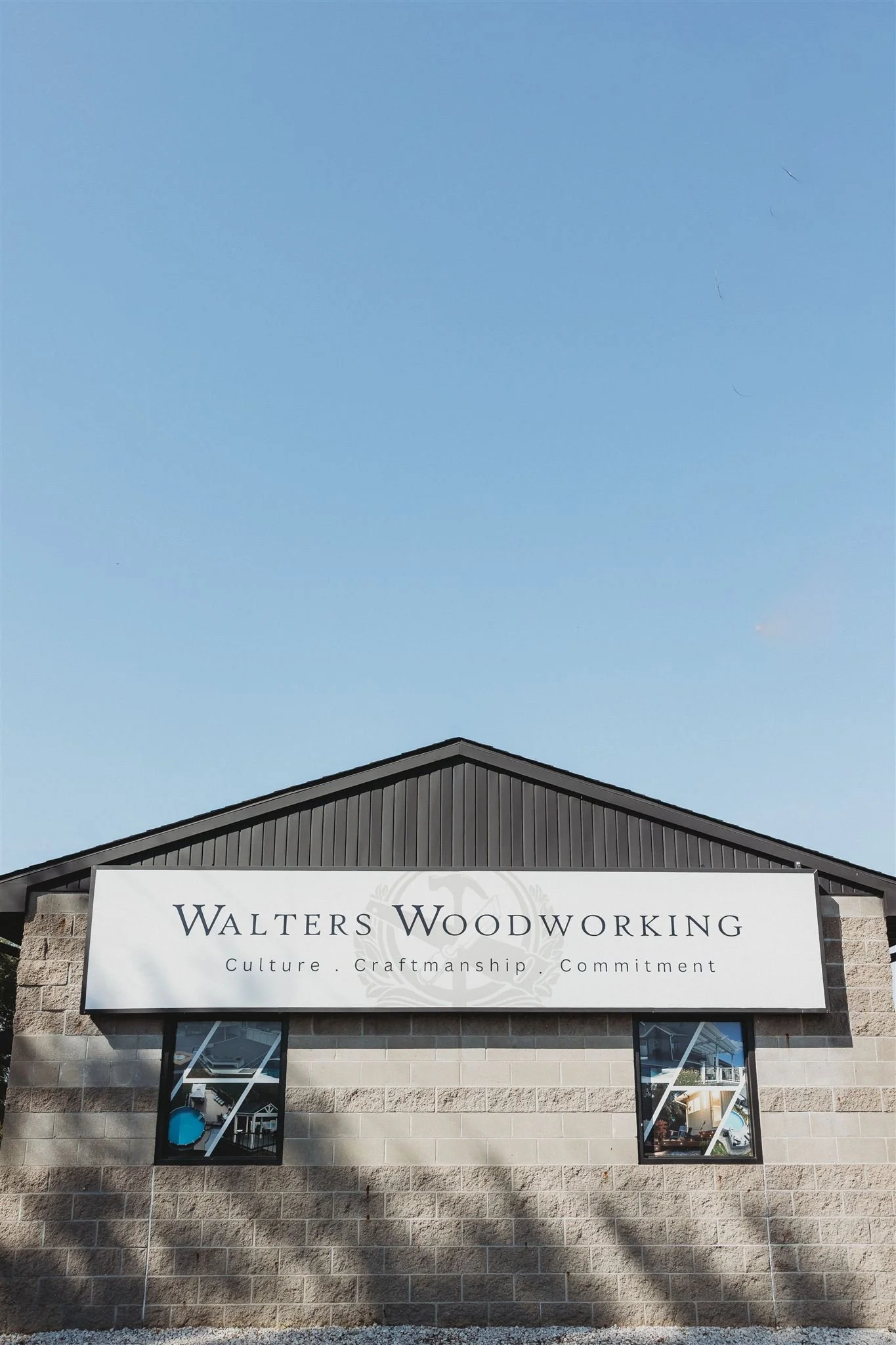 Sign for Walters Woodworking business on a brick building with two windows, under a blue sky.