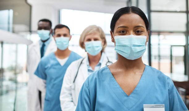 Group of healthcare professionals wearing masks, standing in a hospital or clinic.
