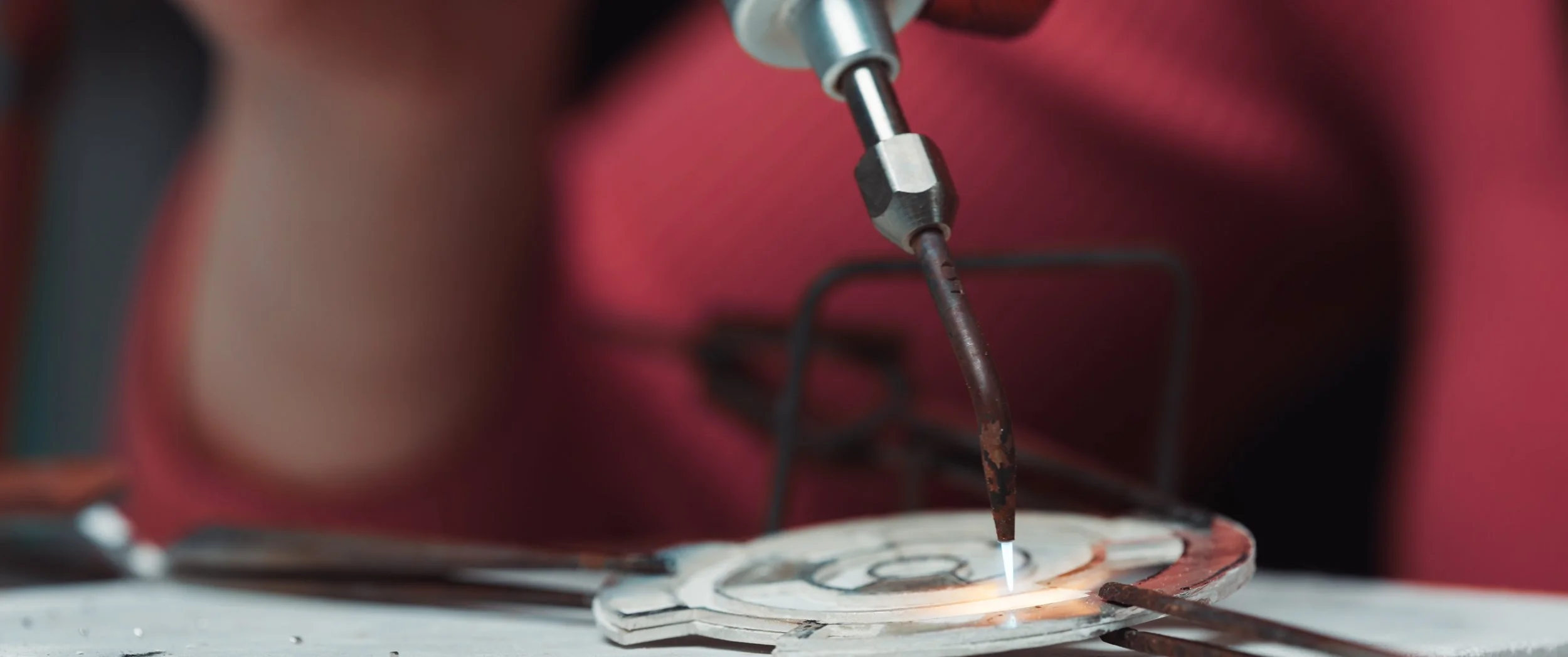 A close-up view of a welding process on a metal object, with a welding tool emitting a bright light and sparks as it joins the metal pieces.