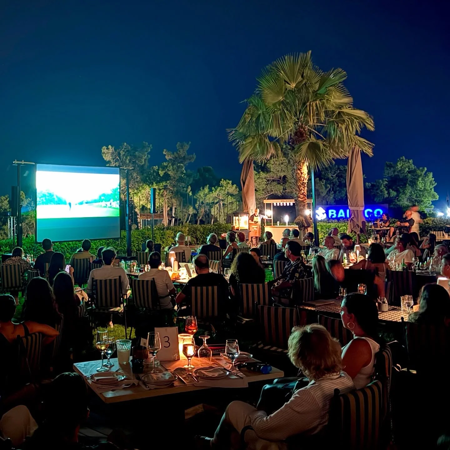 Golf Greece arranges a Clubhouse Serenade to gather the community around its glowing projection screen. Late July in flaming Athens (40+&deg;C) can be such a thrill, as implied by the full garden of Colonial in Glyfada Golf Club. Laughter, diluting i