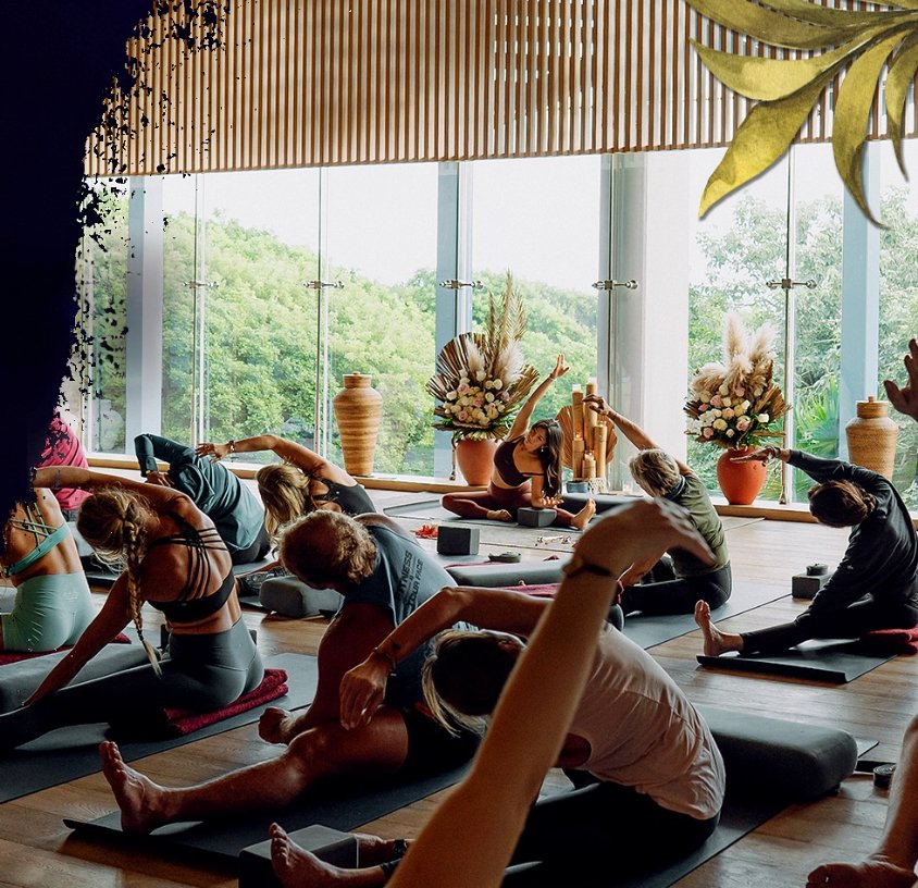 Group yoga class in a studio with large windows and greenery outside.