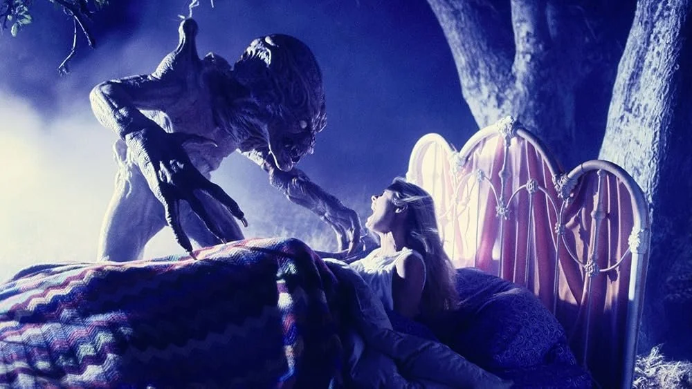 Still from Pumpkinhead II: Sarah is in bed, outside in a field, screaming at Pumpkinhead, who is looming over her
