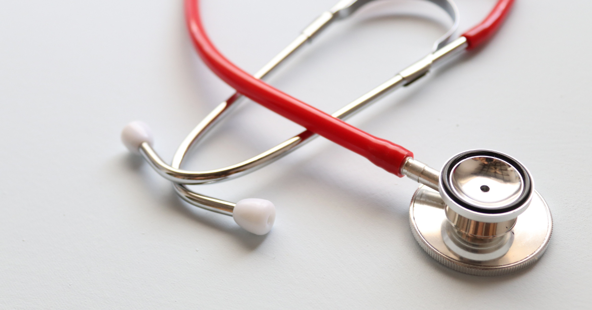 A stethoscope with red tubing and a silver chest piece on a white surface.