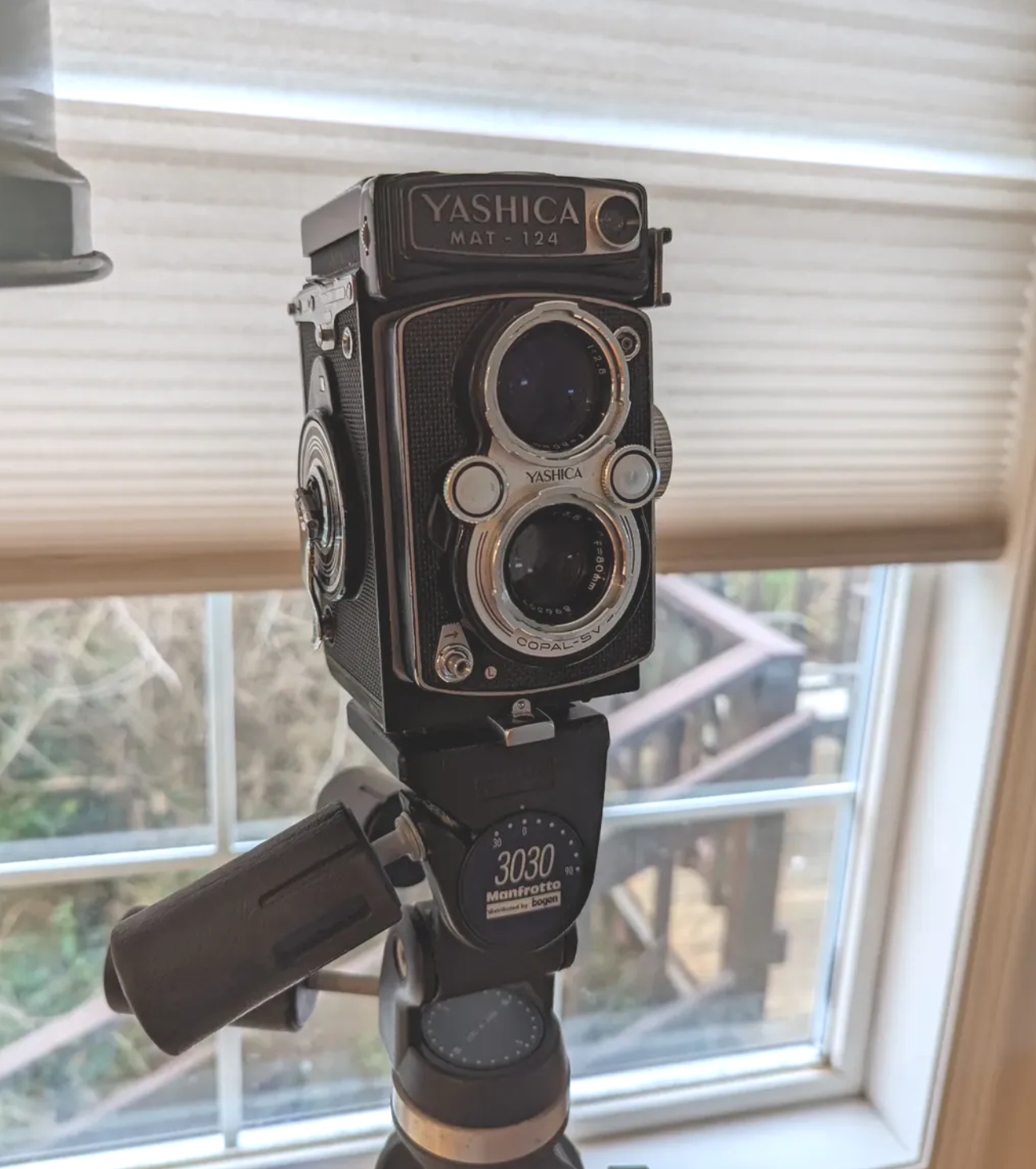 Jake Carlsen's vintage twin-lens reflex camera on a tripod in front of a window with blinds.