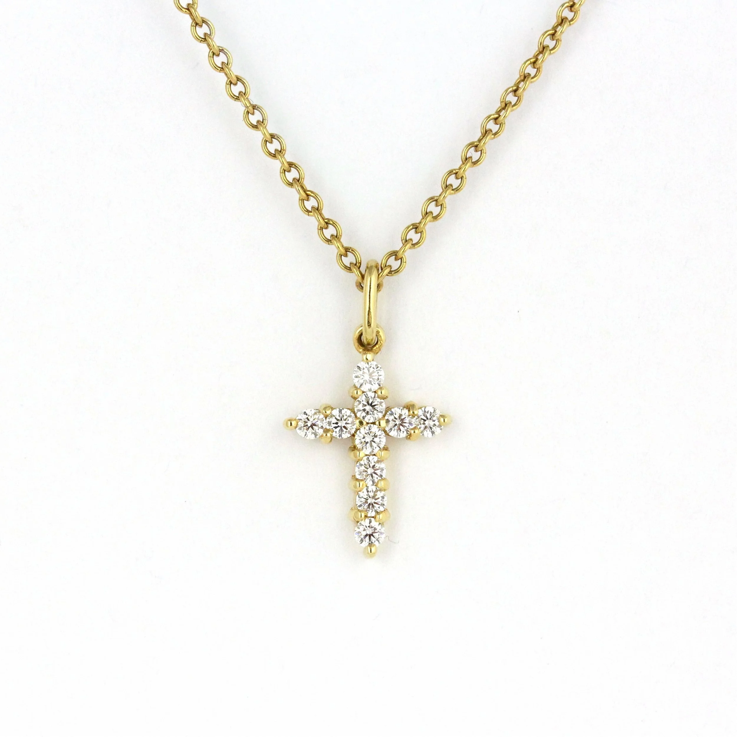 Gold chain necklace with a cross pendant decorated with diamonds on a white background.