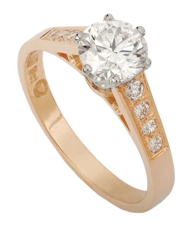 A gold engagement ring with a large round diamond center stone and smaller diamonds along the band.