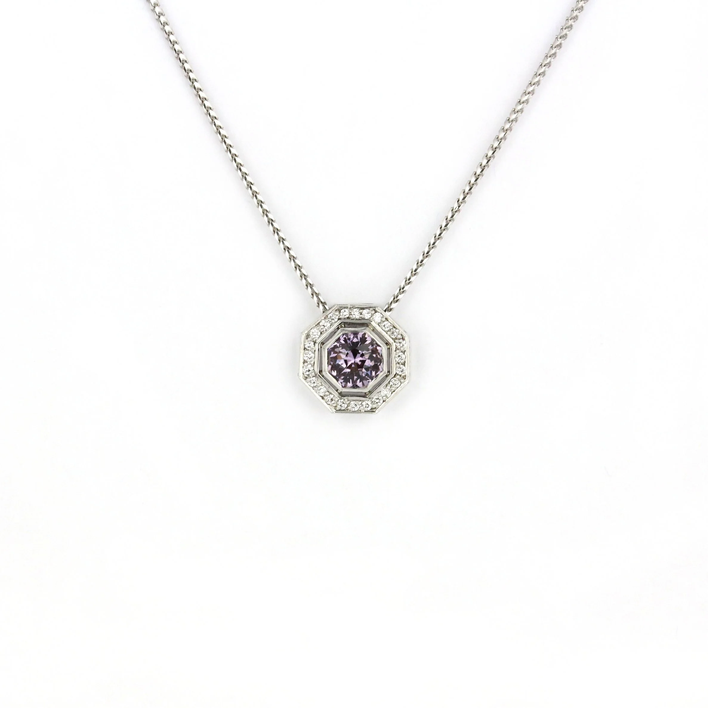 A White gold necklace with an octagonal pendant featuring a purple gemstone surrounded by small diamonds.