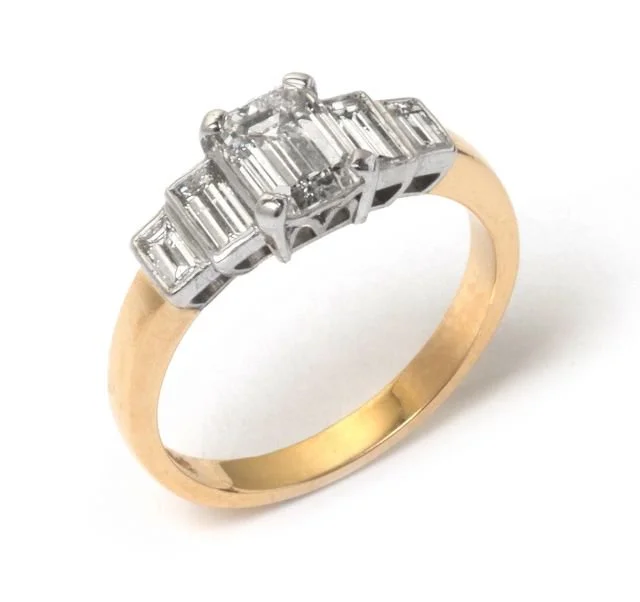 Gold ring with a row of five baguette-cut diamonds set in a silver or platinum setting.