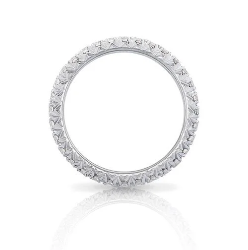 White gold ring with intricate design around the band, reflected on a white surface.