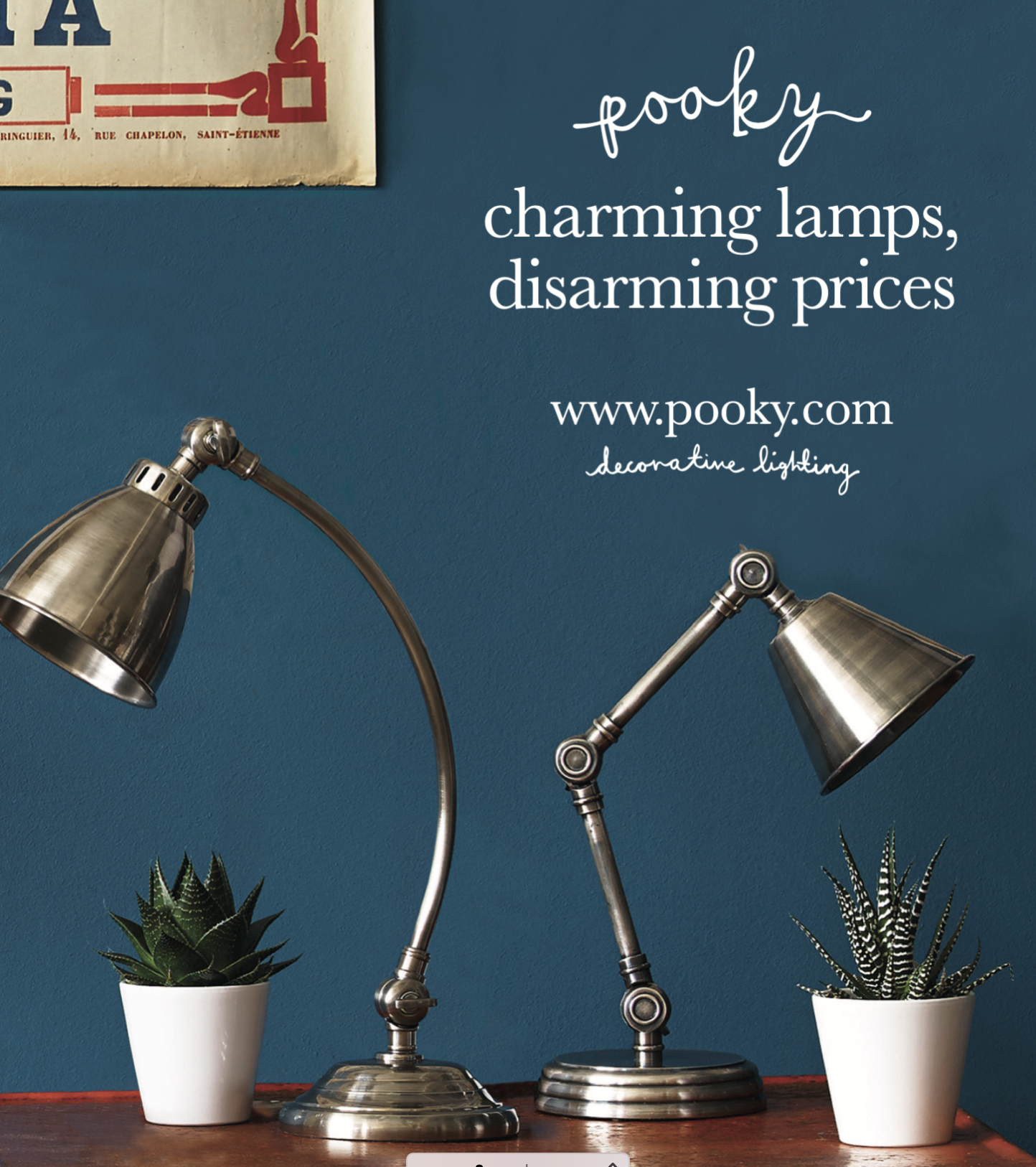 Two metallic desk lamps with adjustable arms and conical shades, placed on a wooden surface with two potted succulents in white pots, against a blue wall with promotional text for Pooky lighting.