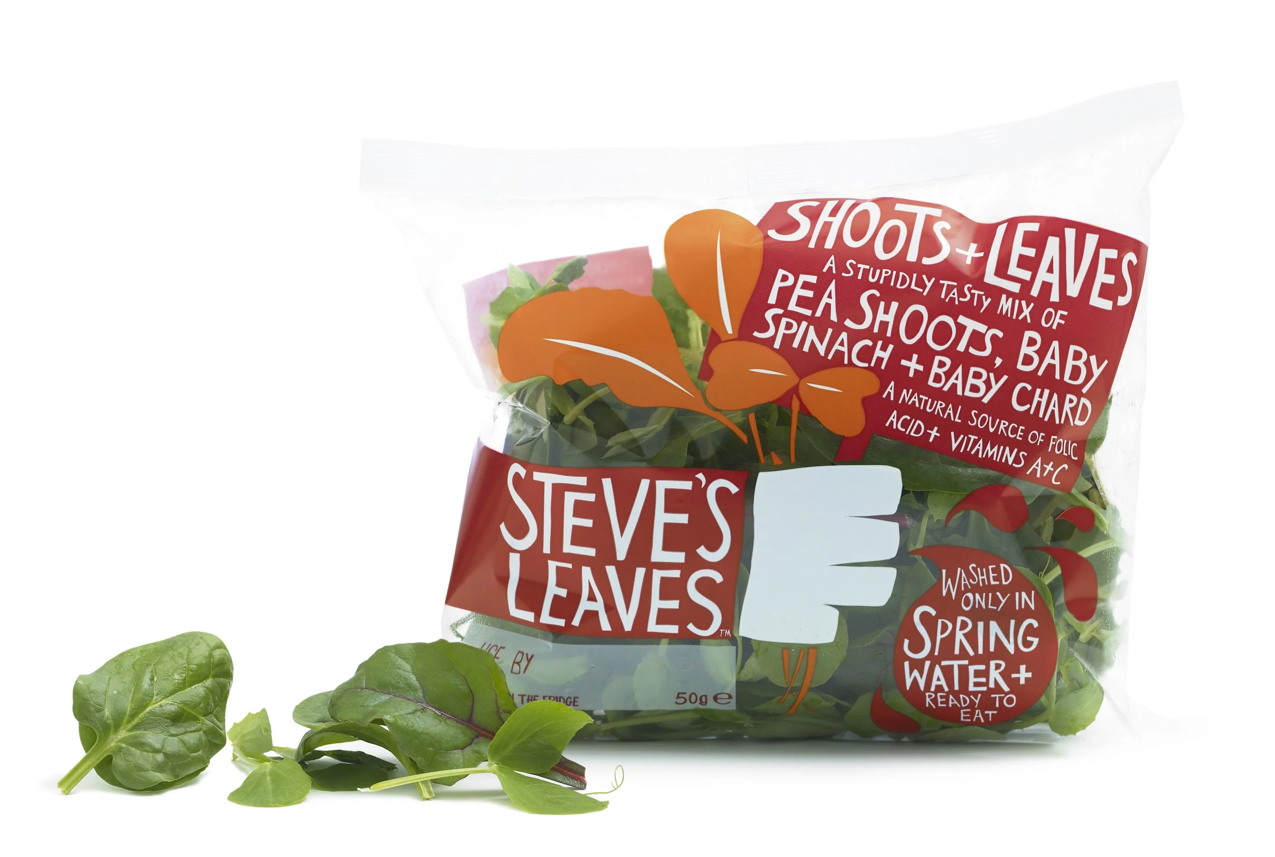 A clear plastic bag of mixed baby salad greens labeled 'Steve's Leaves,' featuring ingredients like pea shoots, spinach, and baby chard, with an illustration of orange leaves. The packaging indicates the greens are washed only in spring water and rea