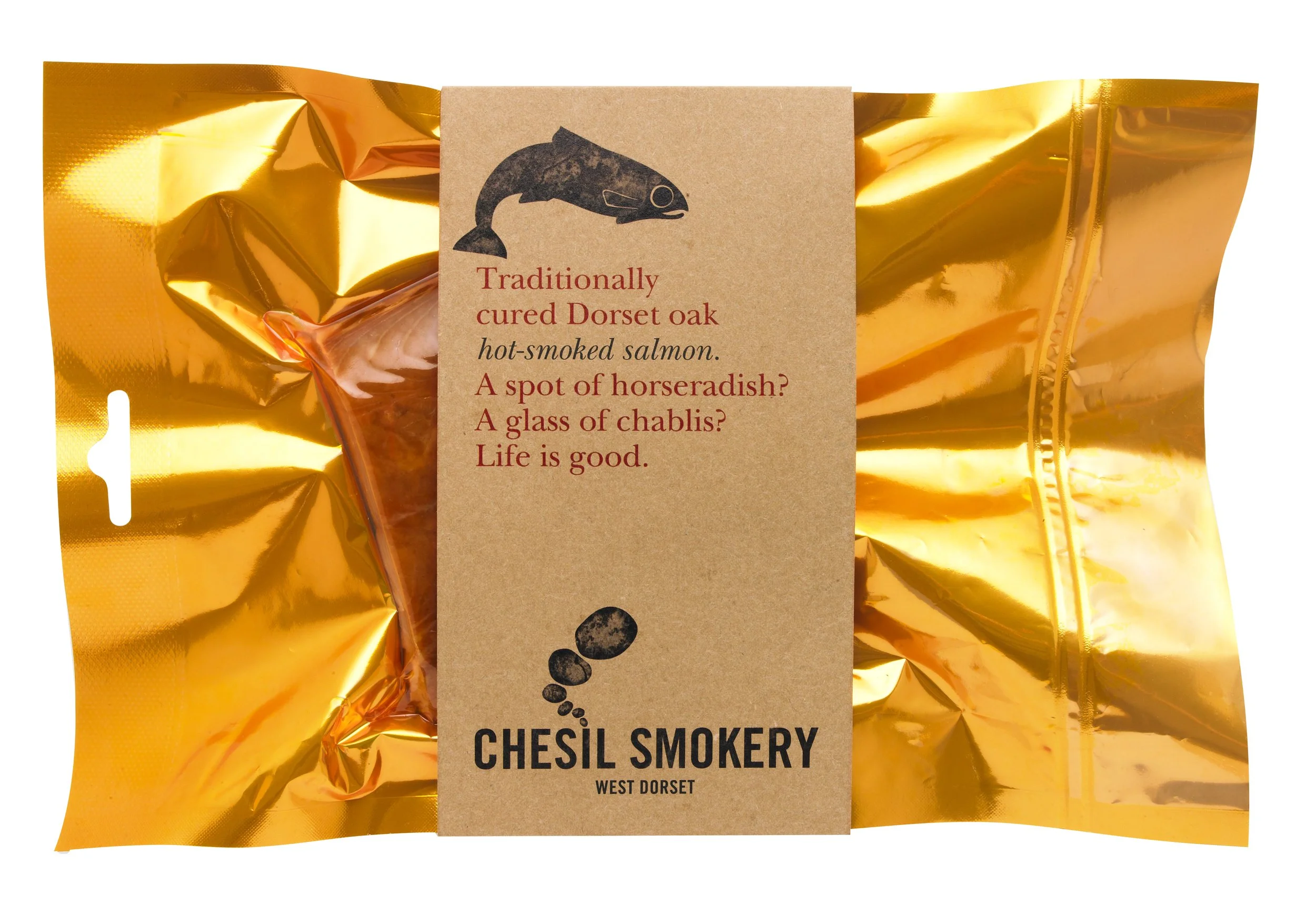 Golden foil packaged smoked salmon from Chesil Smokery West Dorset with a brown label featuring a fish illustration and a poetic description about cured Dorset oak hot-smoked salmon.