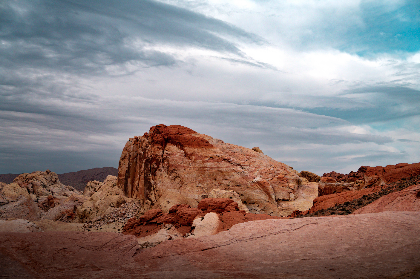 Desert landscape with large red and white rocks and a cloudy sky.