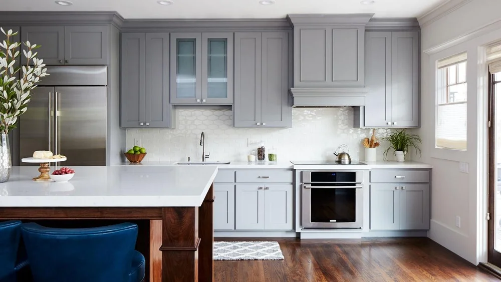Kitchen with grey cabinets, white countertops and stainless steel appliances.