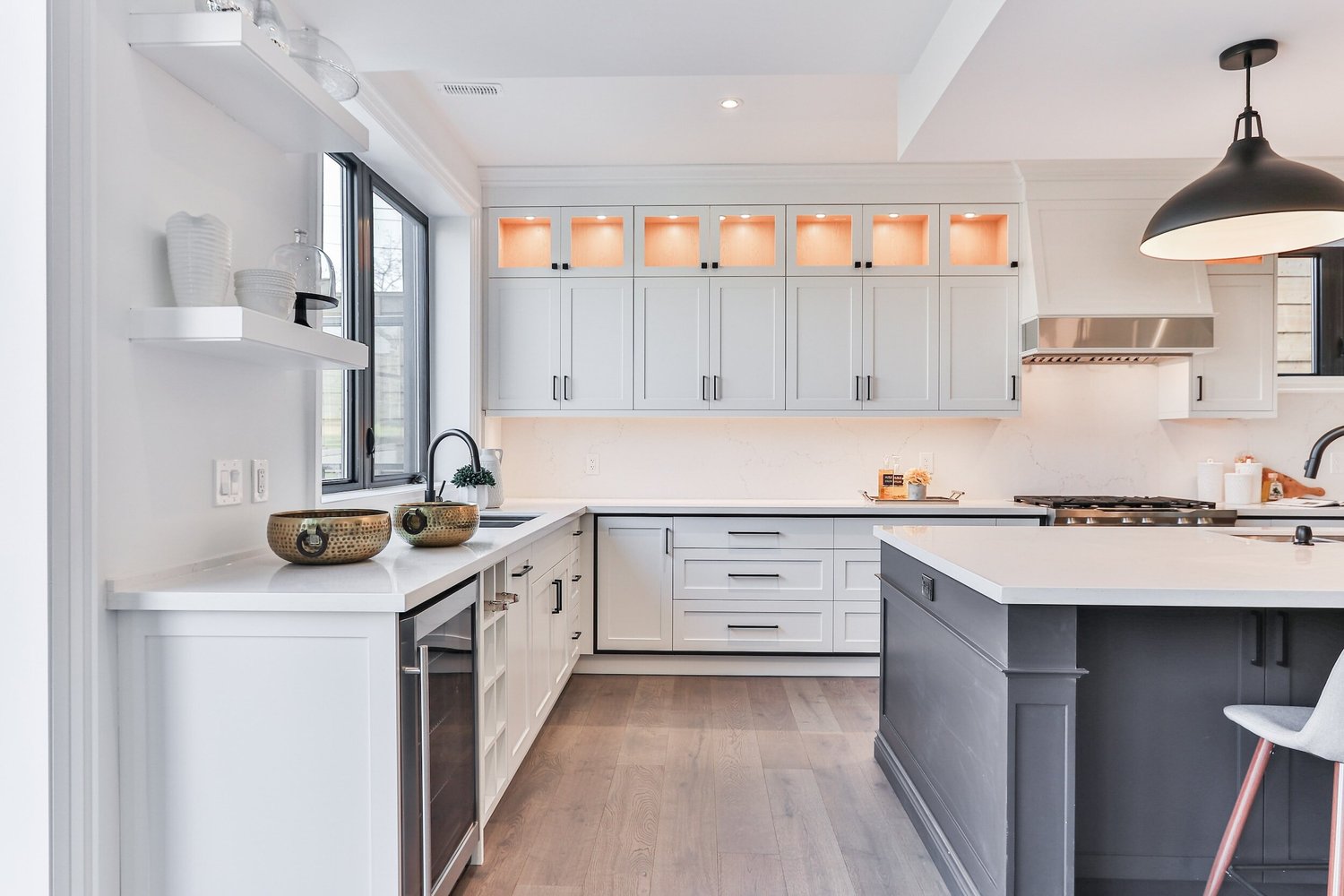 Bright kitchen with white cabinets, a dark island and warm wood flooring.