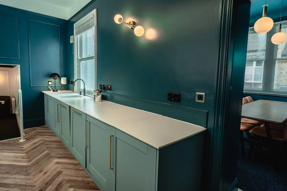 Kitchen with teal cabinets and white countertops.