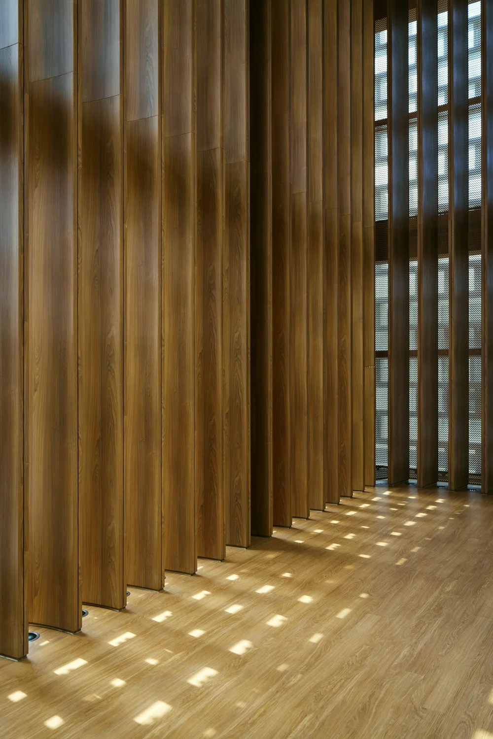 Interior wood slat wall and wood flooring in natural light.