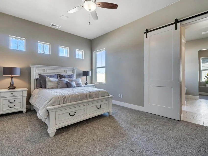 Modern bedroom with gray walls, white bed frame, and ceiling fan.