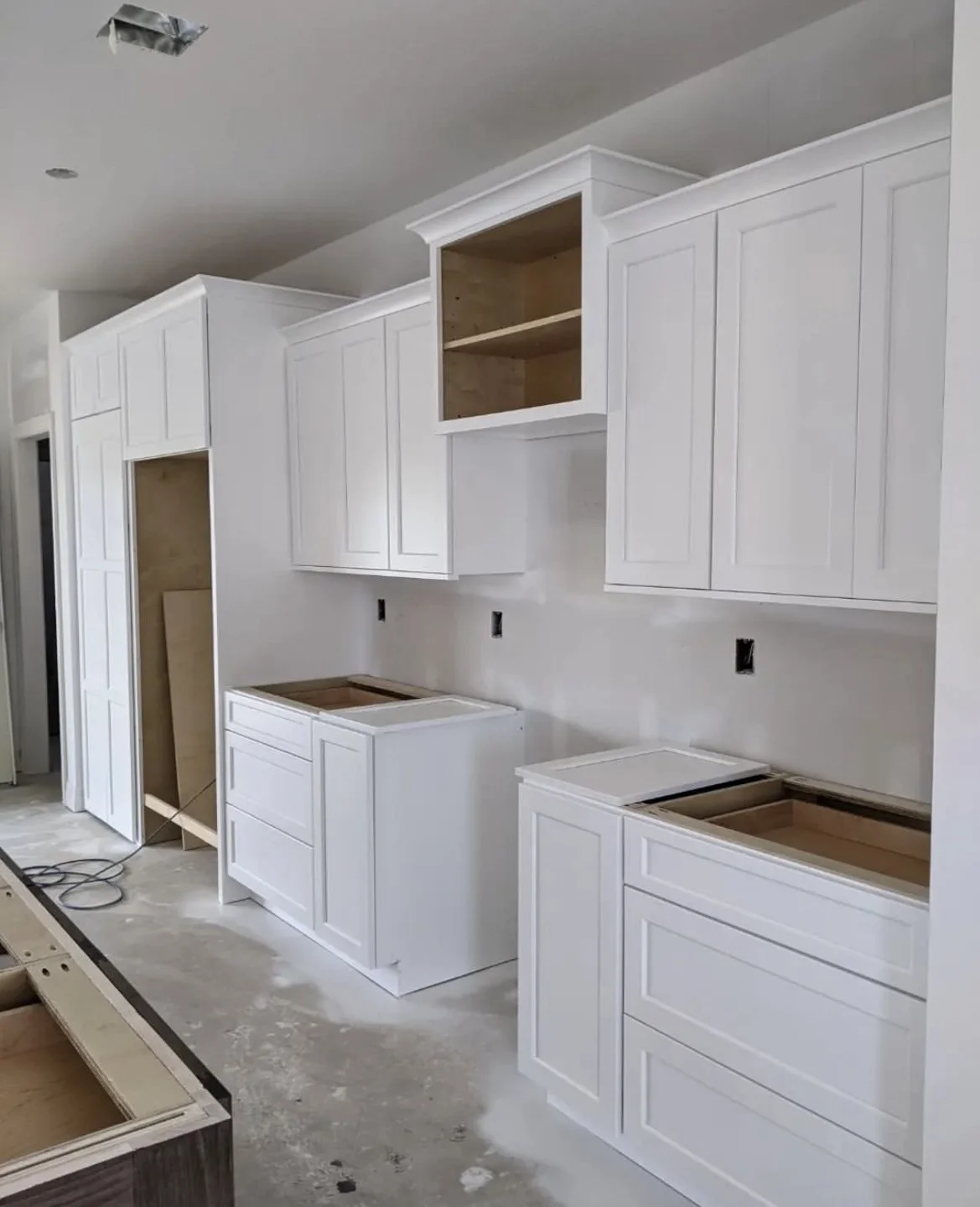 Kitchen under construction with white cabinetry