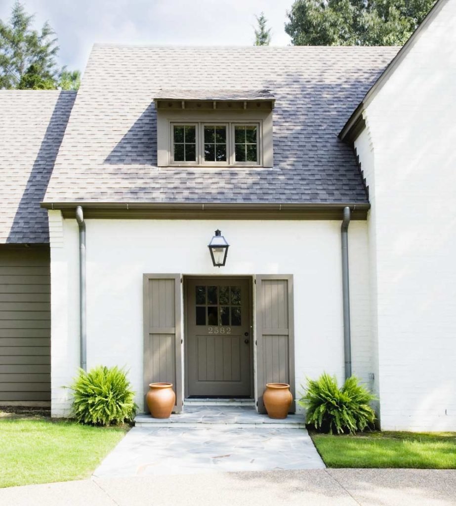 White home exterior with grey shutters, a front entrance and a stone pathway.