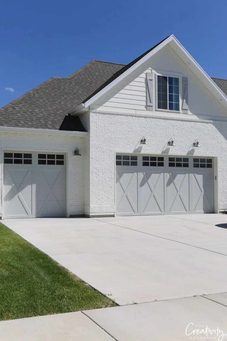 Light-coloured home exterior with three garage doors and contrasting roof.