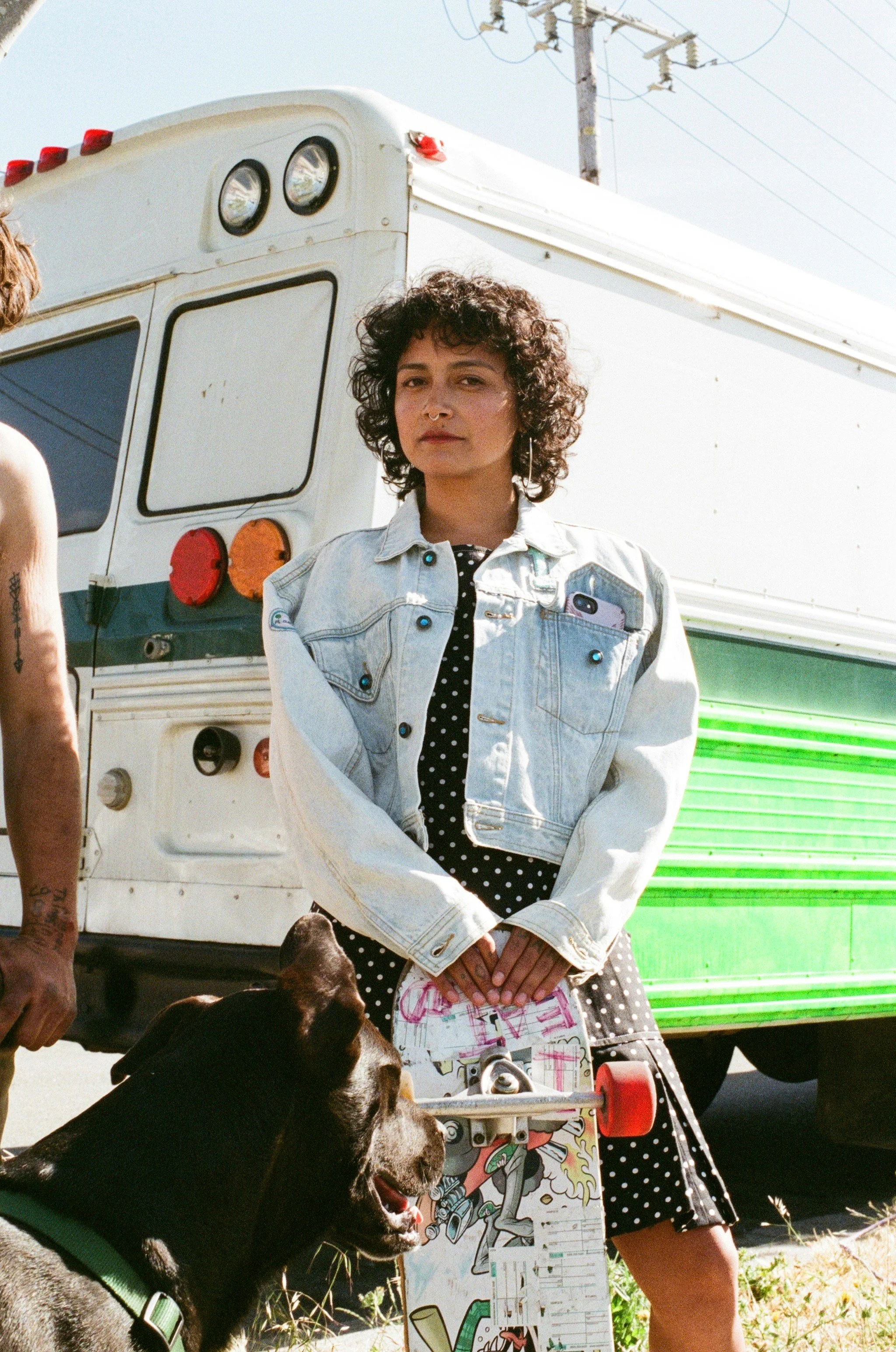 non-binary person posing with a skateboard and a dog in front of a van