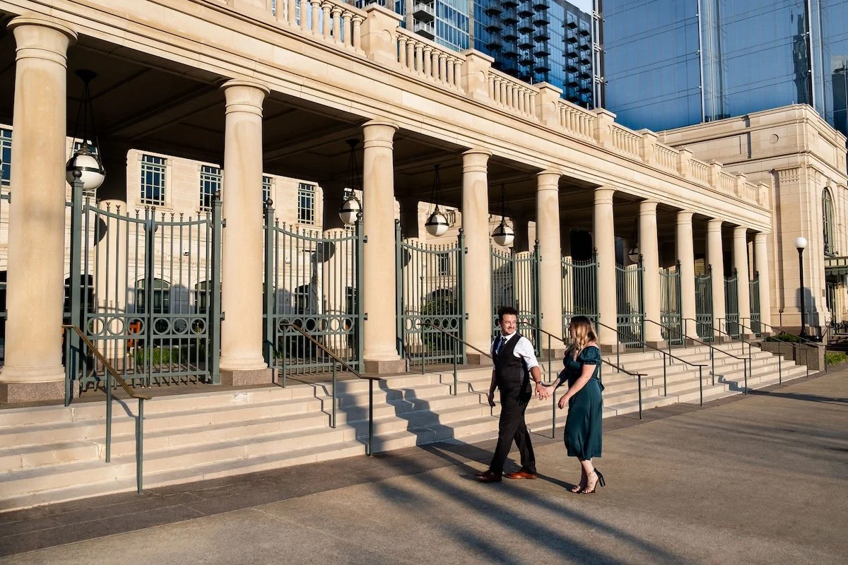 A couple walks hand in hand at golden hour, outside of the symphony center in Nashville, TN.