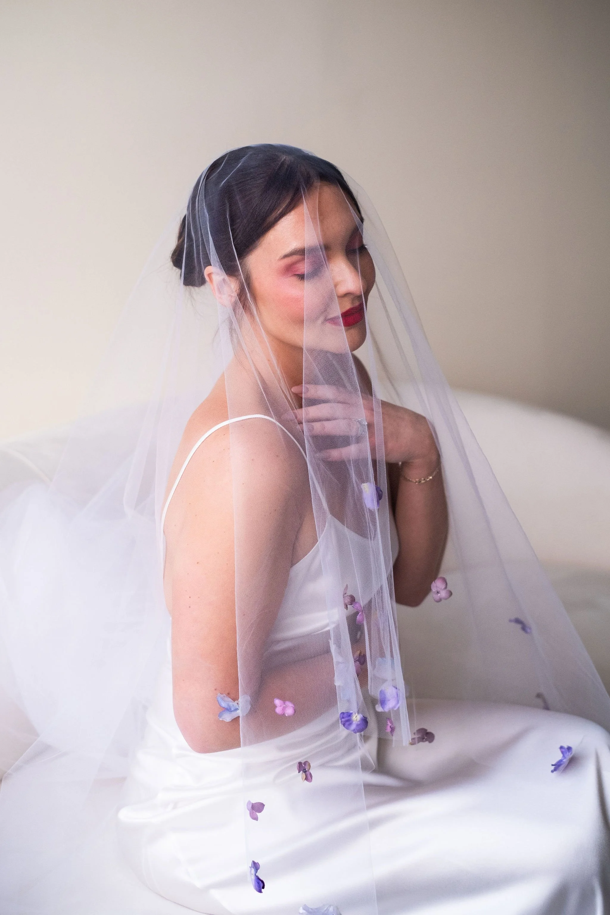A bride sitting in her wedding dress, under her veil, taking a moment to herself.