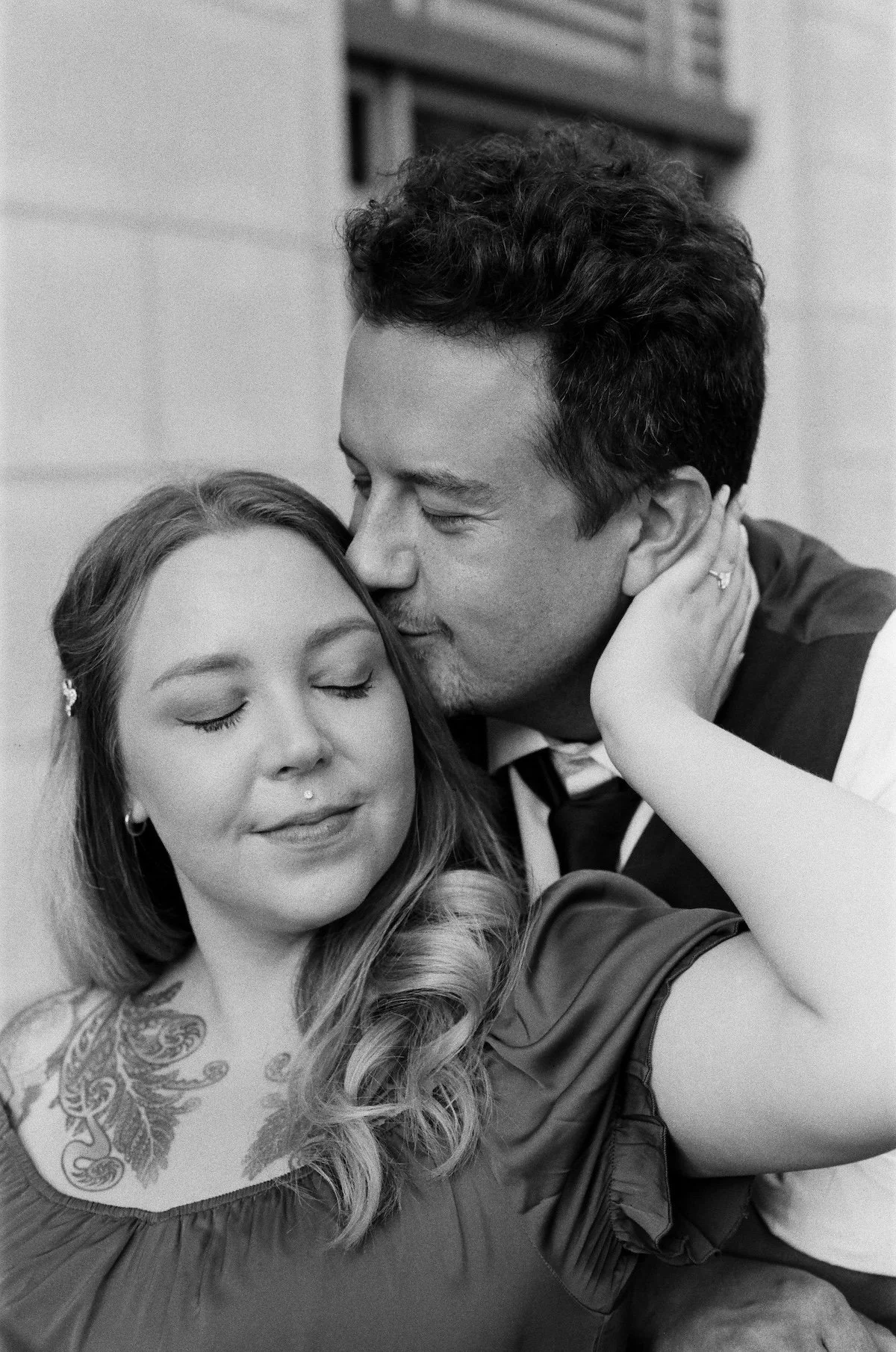 A man kisses his fiancé on her temple.