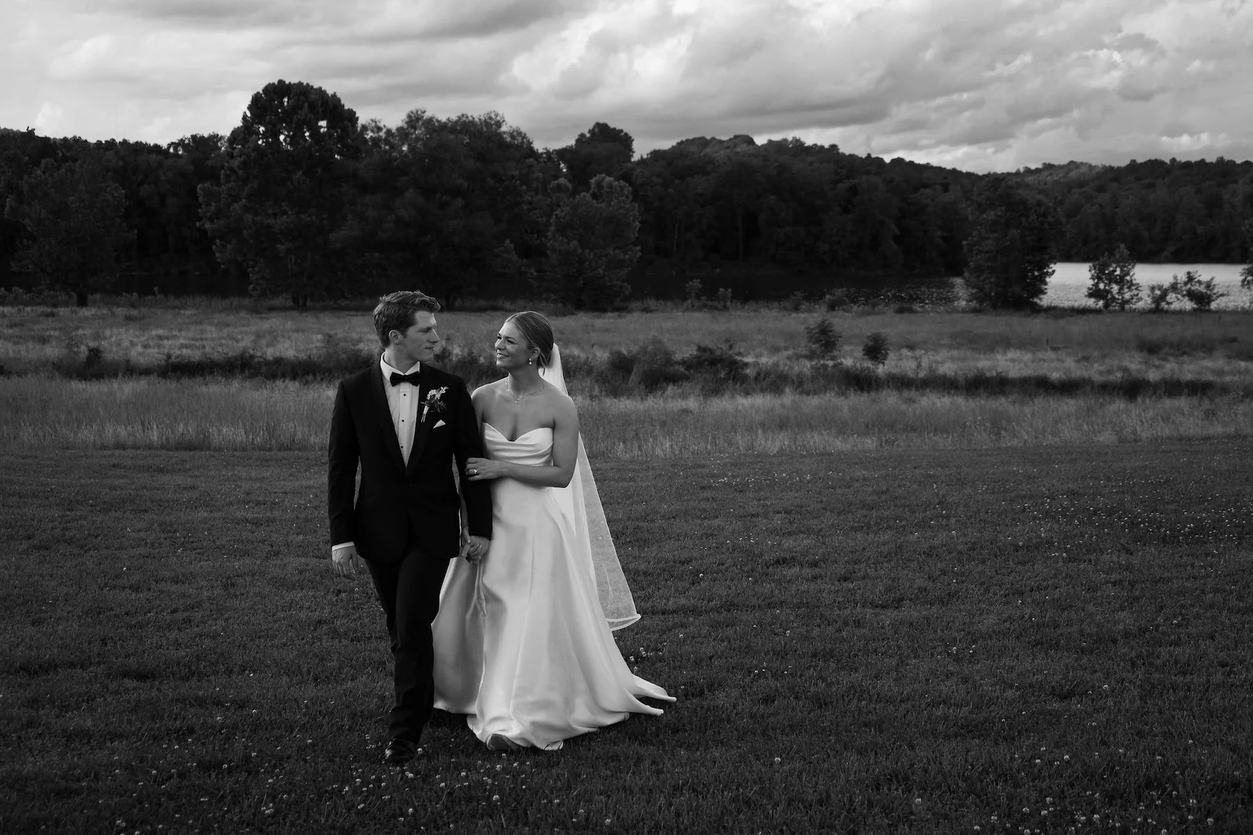 A bride and groom walk through a Tennessee field during golden hour.