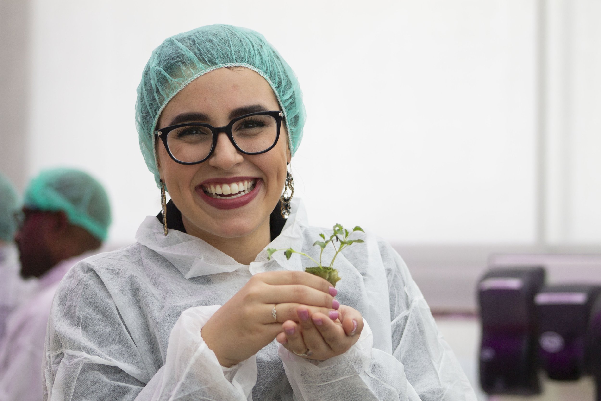 An Eden Green employee smiles holding a sprouting plant in her hands