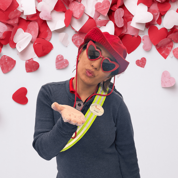 chick-fil-A team member blowing a kiss  wearing a red hat and heart sunglasses