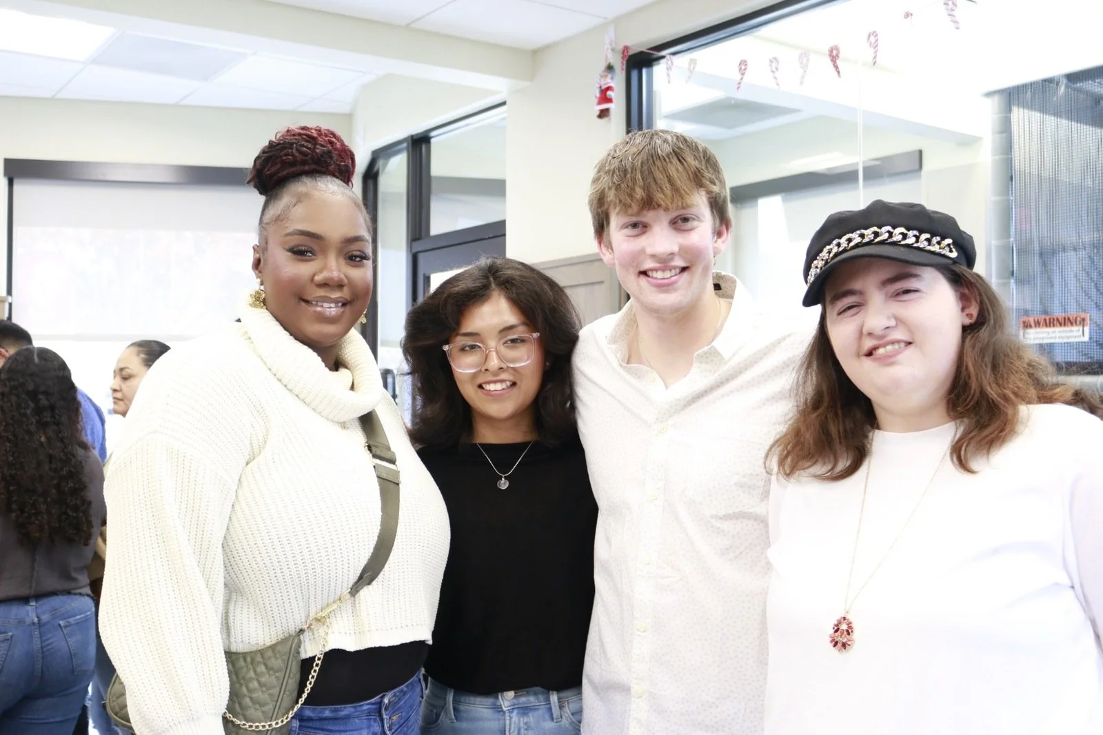 1. Evan Olson in a white shirt standing with three others at a Christmas gathering inside Chick-fil-A.