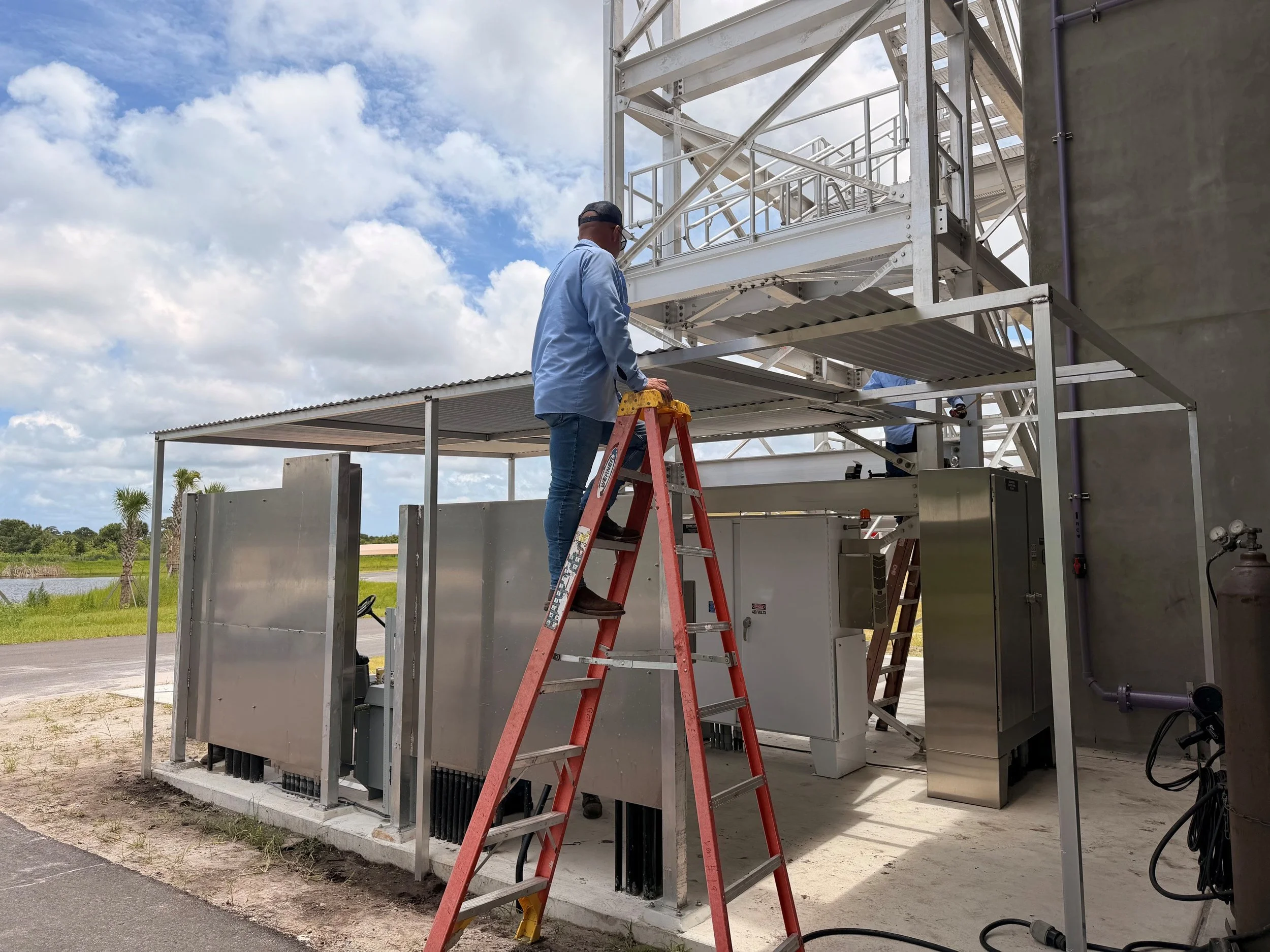 Maintenance team constructing protective canopy over headworks electrical panel