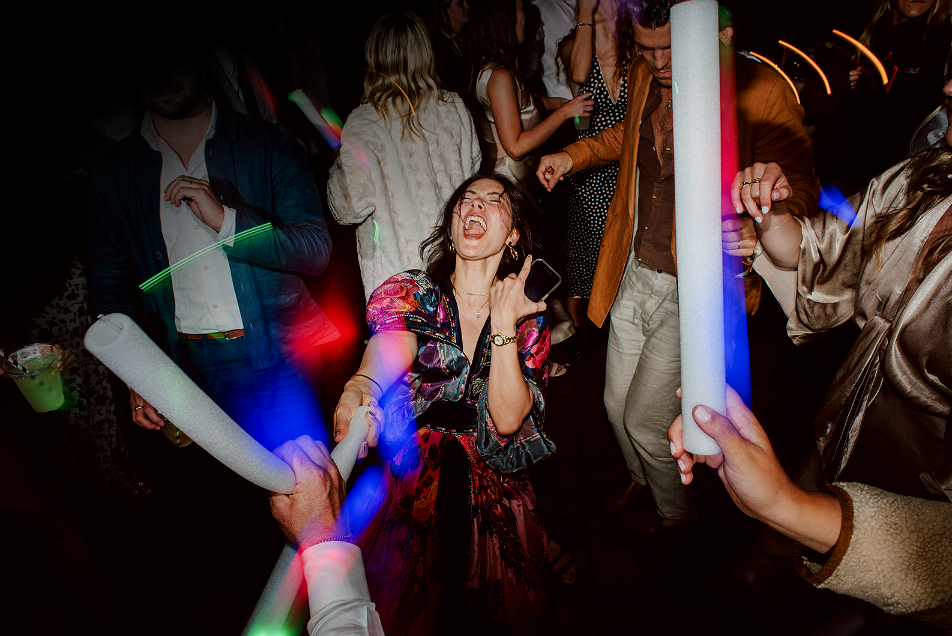 Wedding guests dancing with glow sticks during an energetic Los Angeles wedding reception by Groove Approved