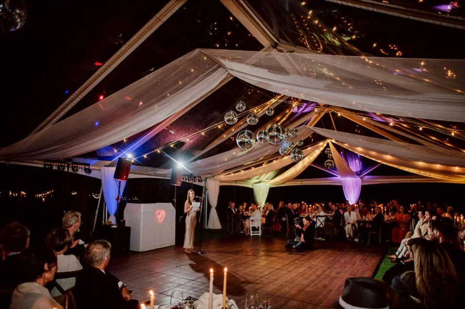 Elegant wedding reception tent with ambient lighting, disco ball, and dance floor by Groove Approved in Southern California