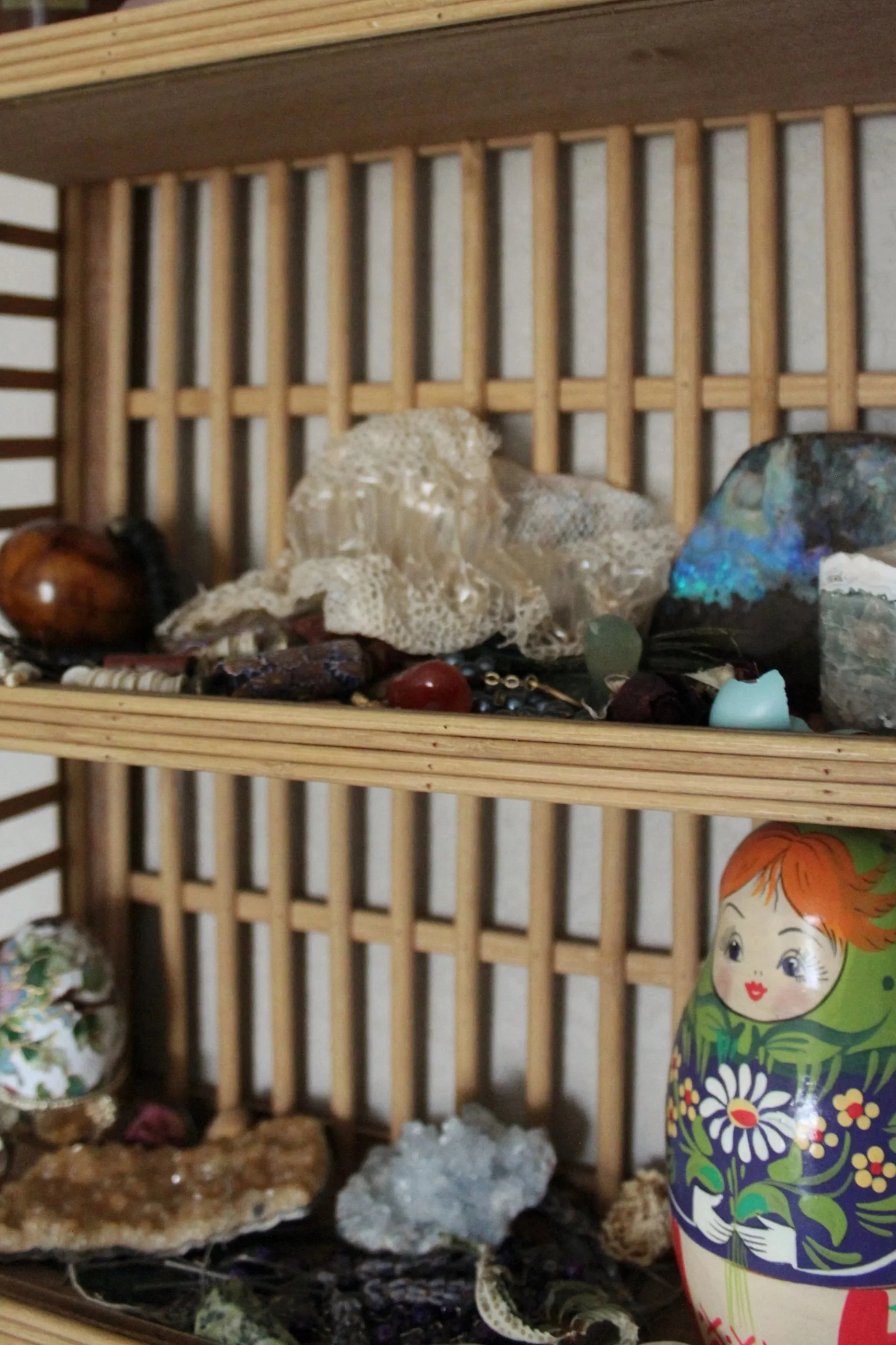 A display of various rocks, a decorative box, and a Russian nesting doll on a wooden shelf.