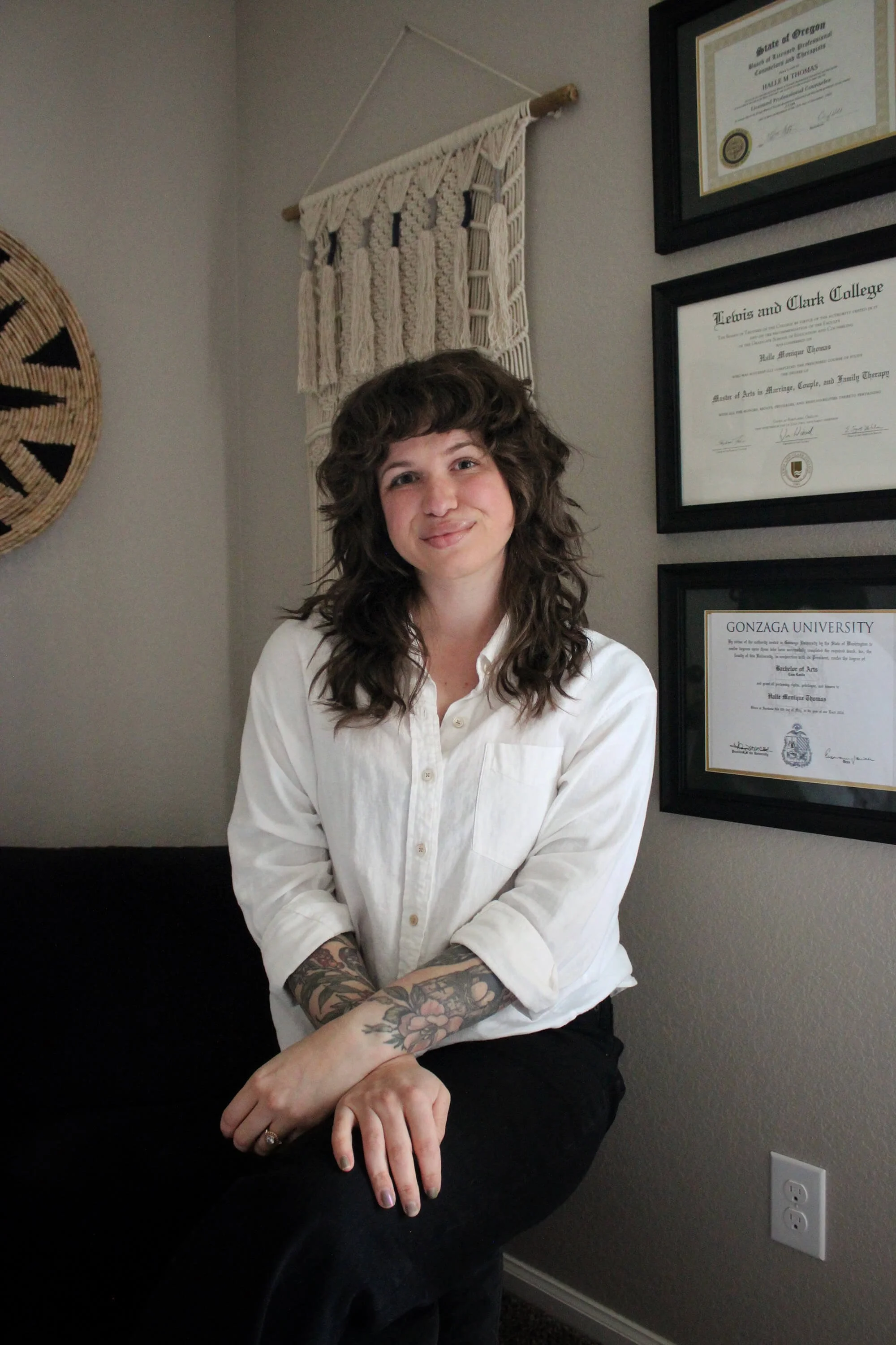 Halle poses in an office, wearing a white button-up while preparing to speak on anxiety and mental health treatments that help with anxiety symptom relief