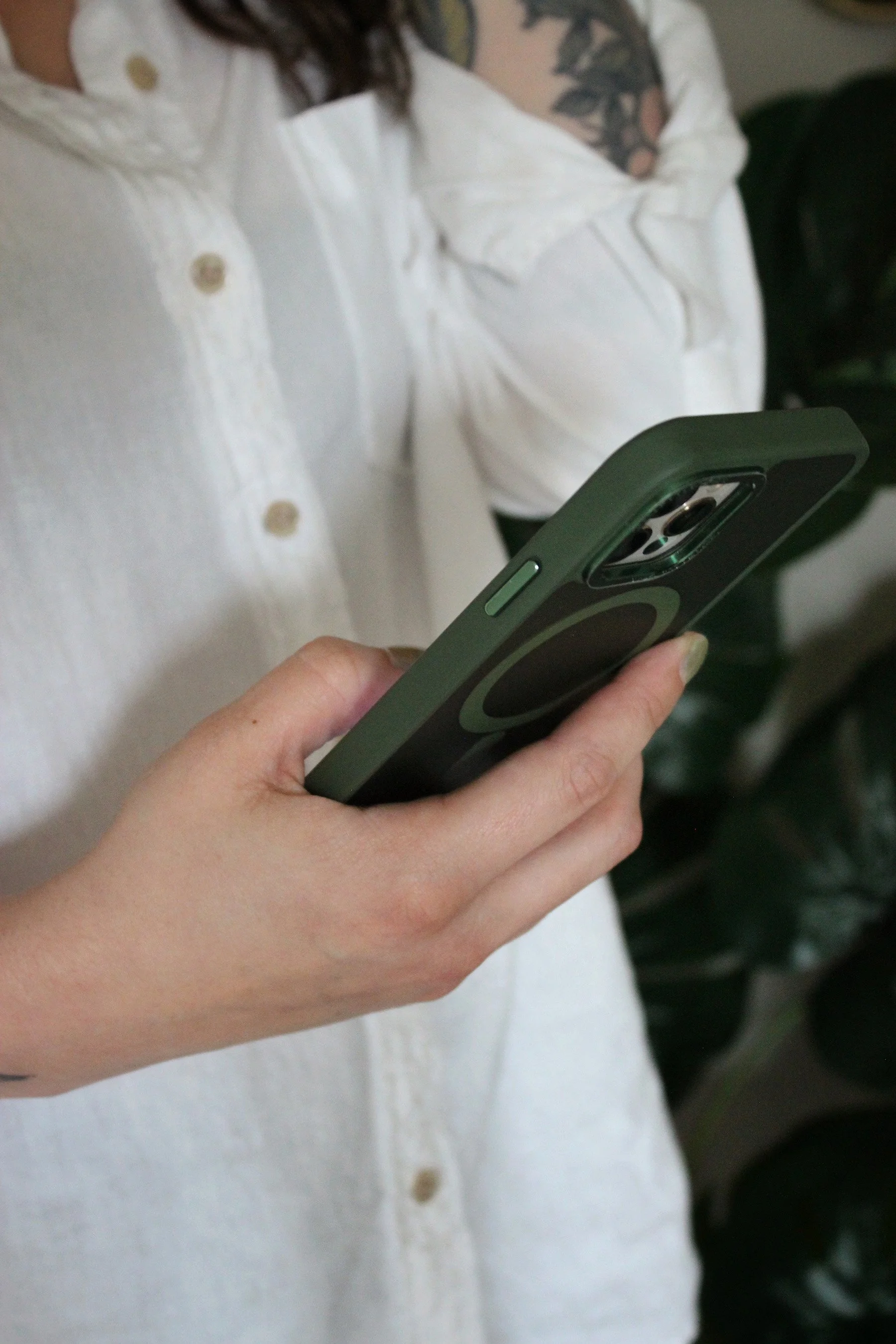 Halle, an anxiety therapist for overthinkers in CO and OR, holding a green phone while wearing a white shirt and speaking to a client during a consultation