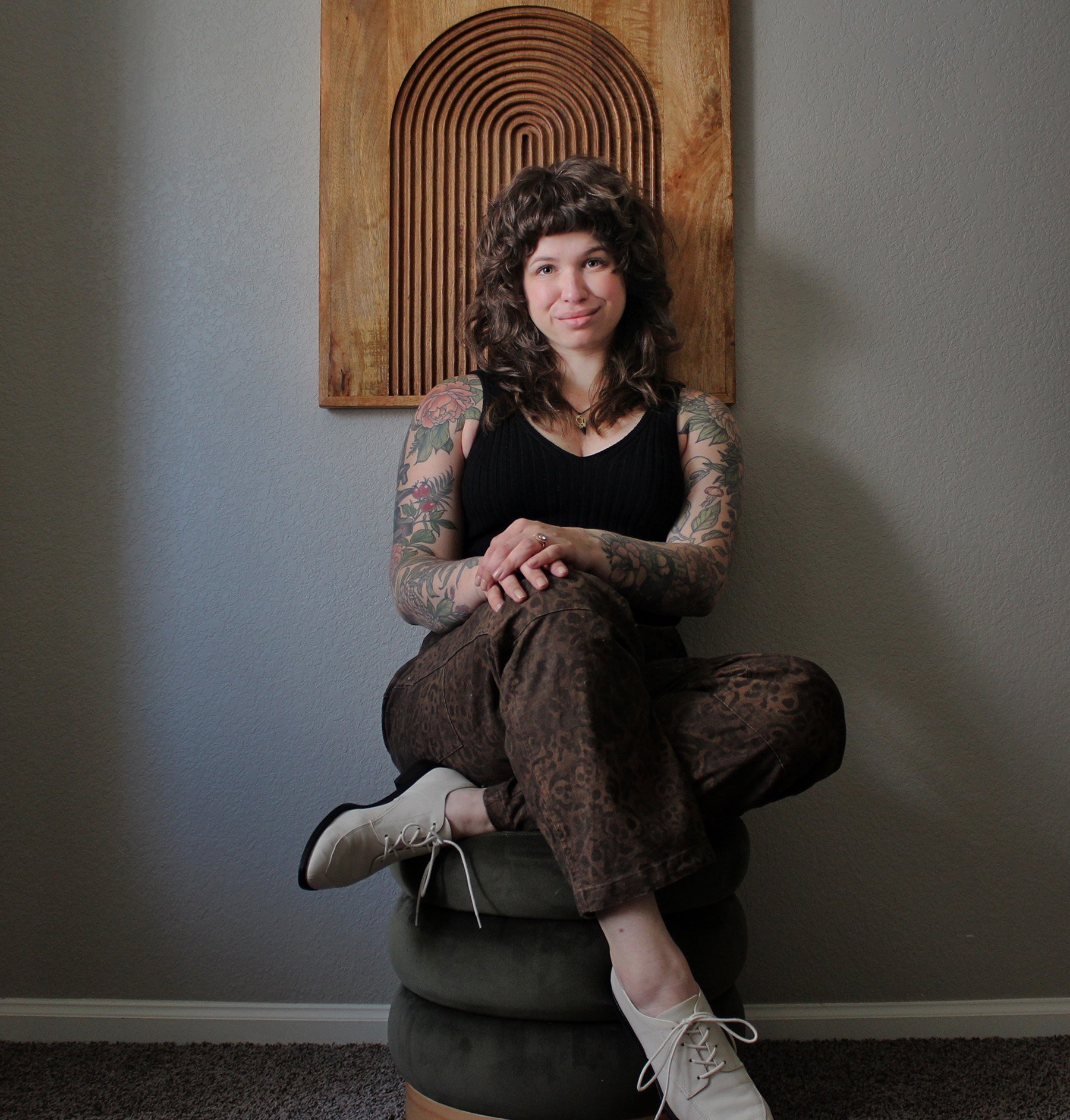 Image of licensed anxiety therapist Halle Thomas sitting on a green stool.