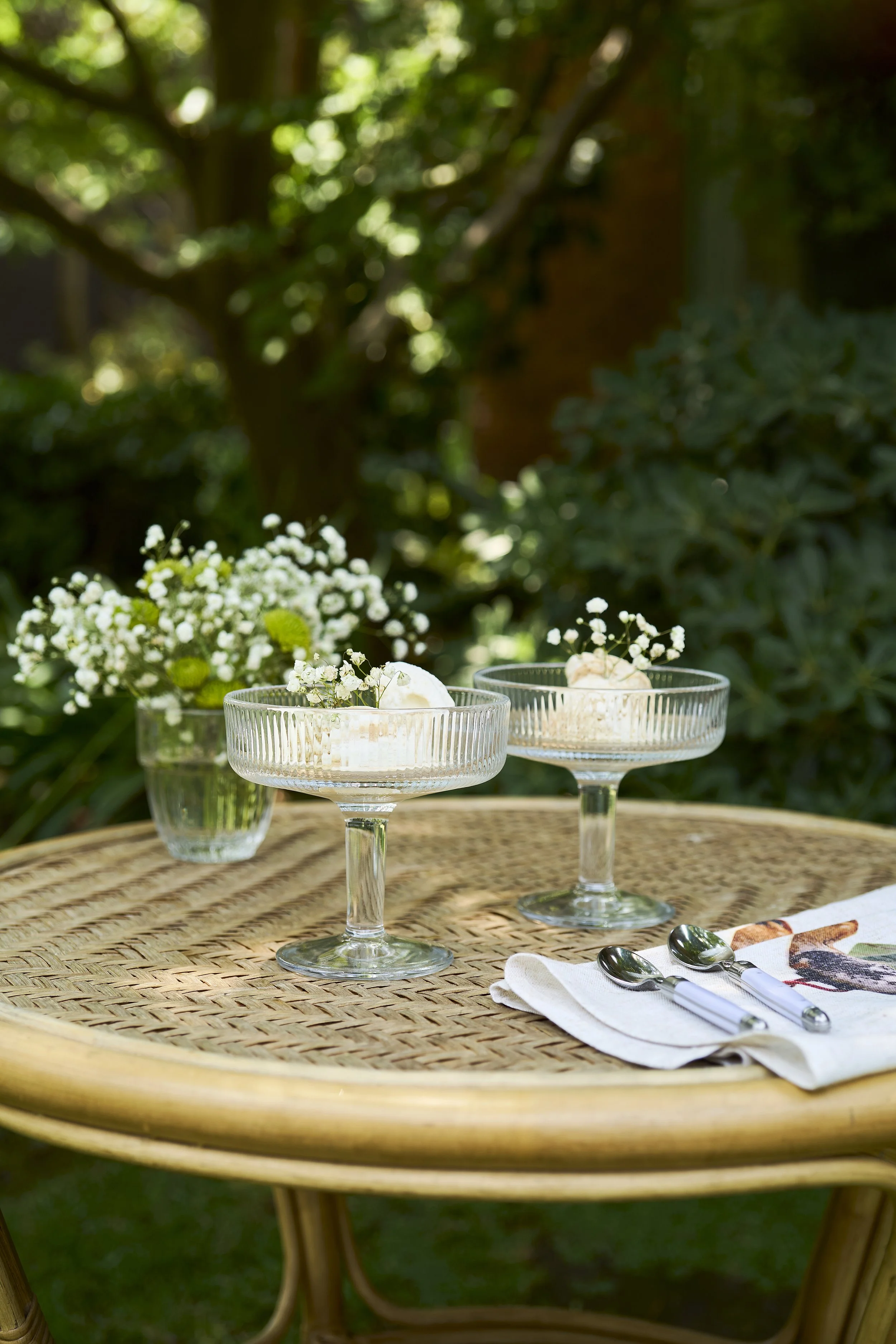 Fotografía de producto lifestyle con mesa de terraza, copas y tablas de cóctel al aire libre.